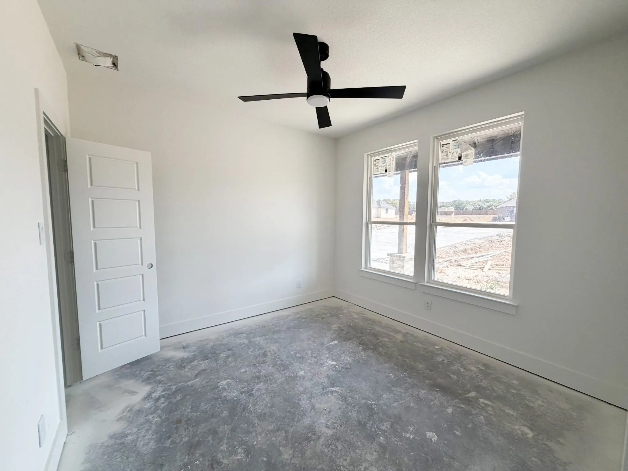 White interior walls with two large windows and a contemporary ceiling fan