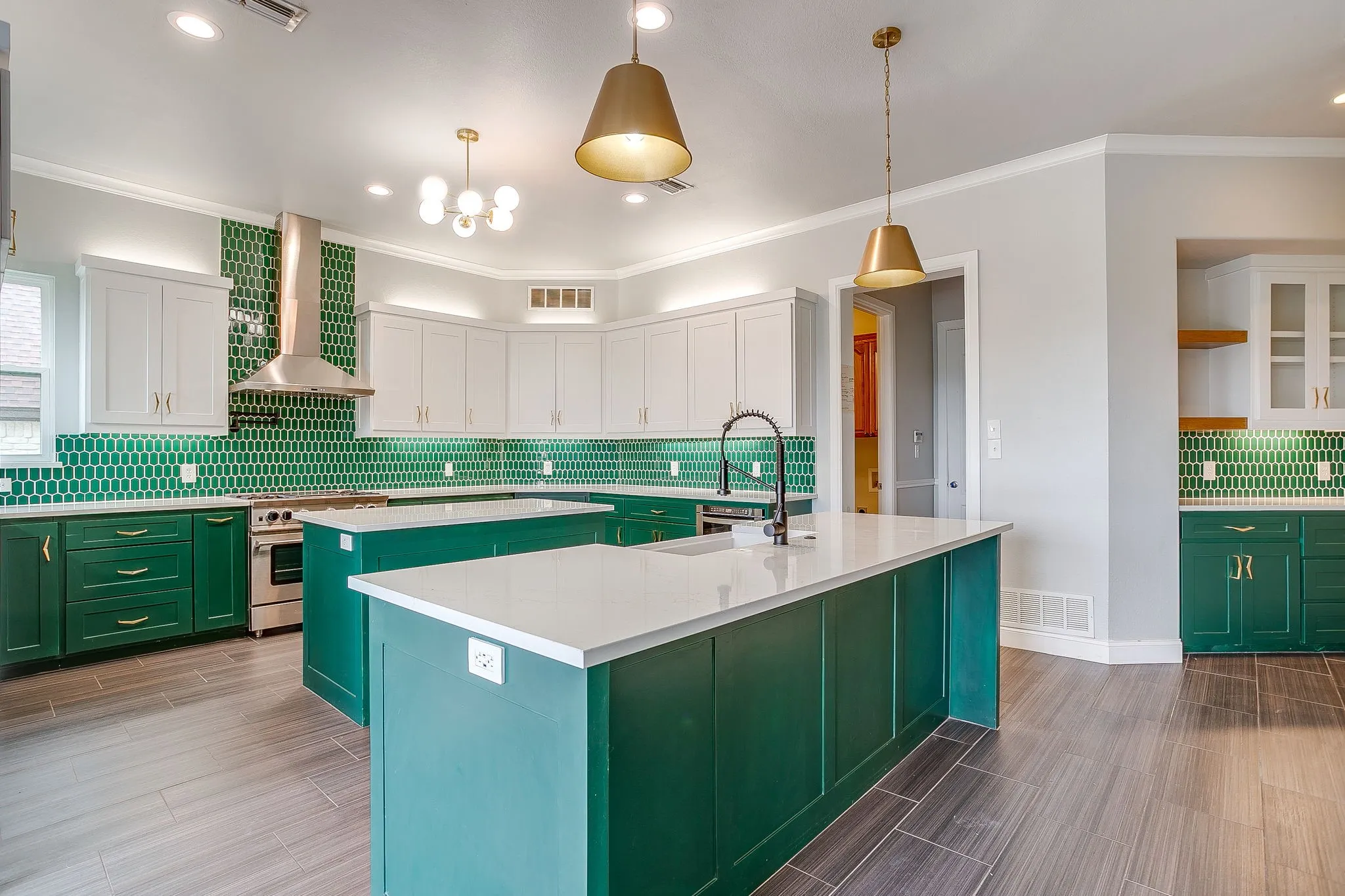 This kitchen features two large islands with white countertops and a black faucet, complemented by green lower cabinets and white upper cabinets