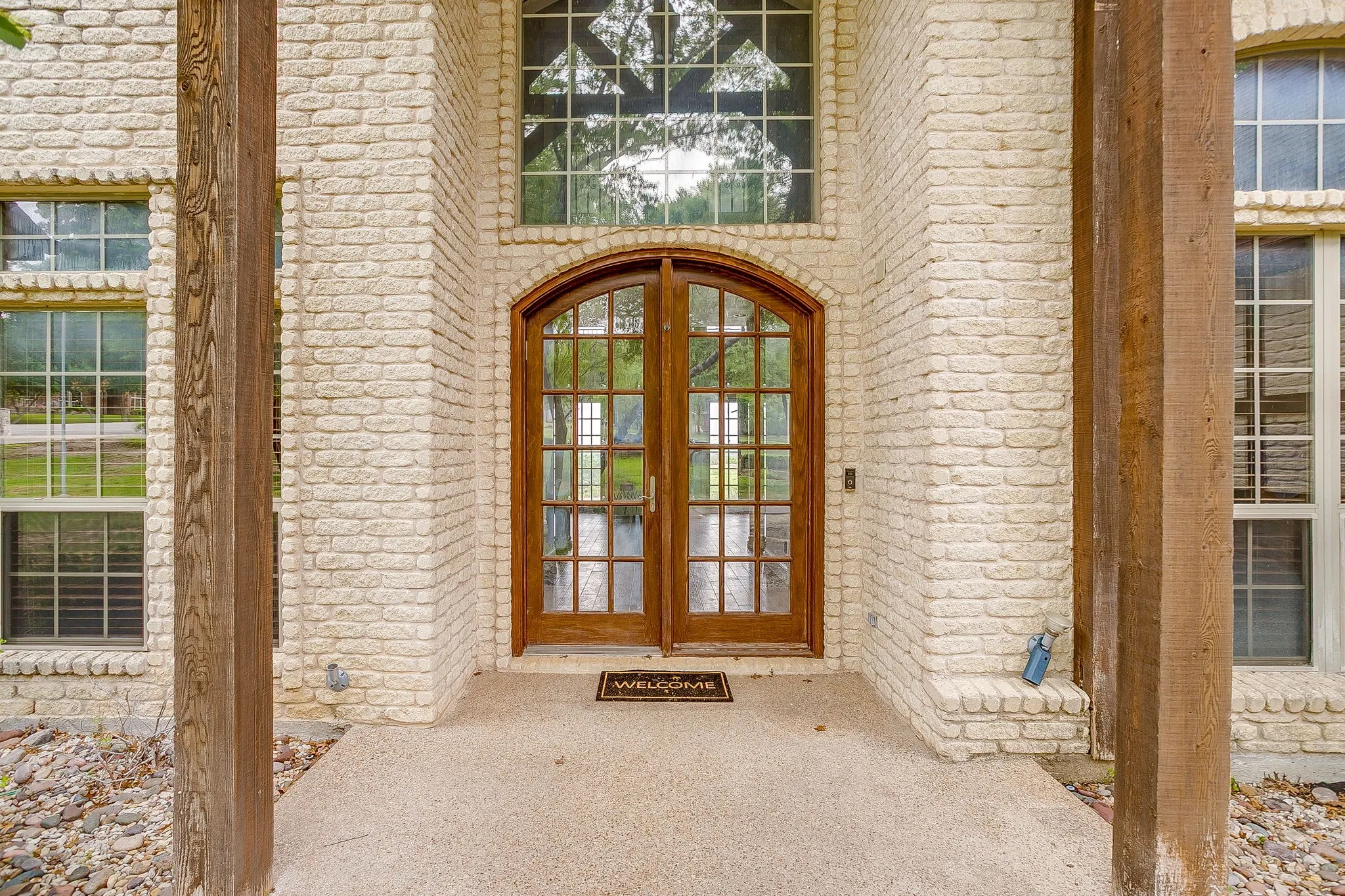 The property features a light brick exterior and an arched wooden double door entry