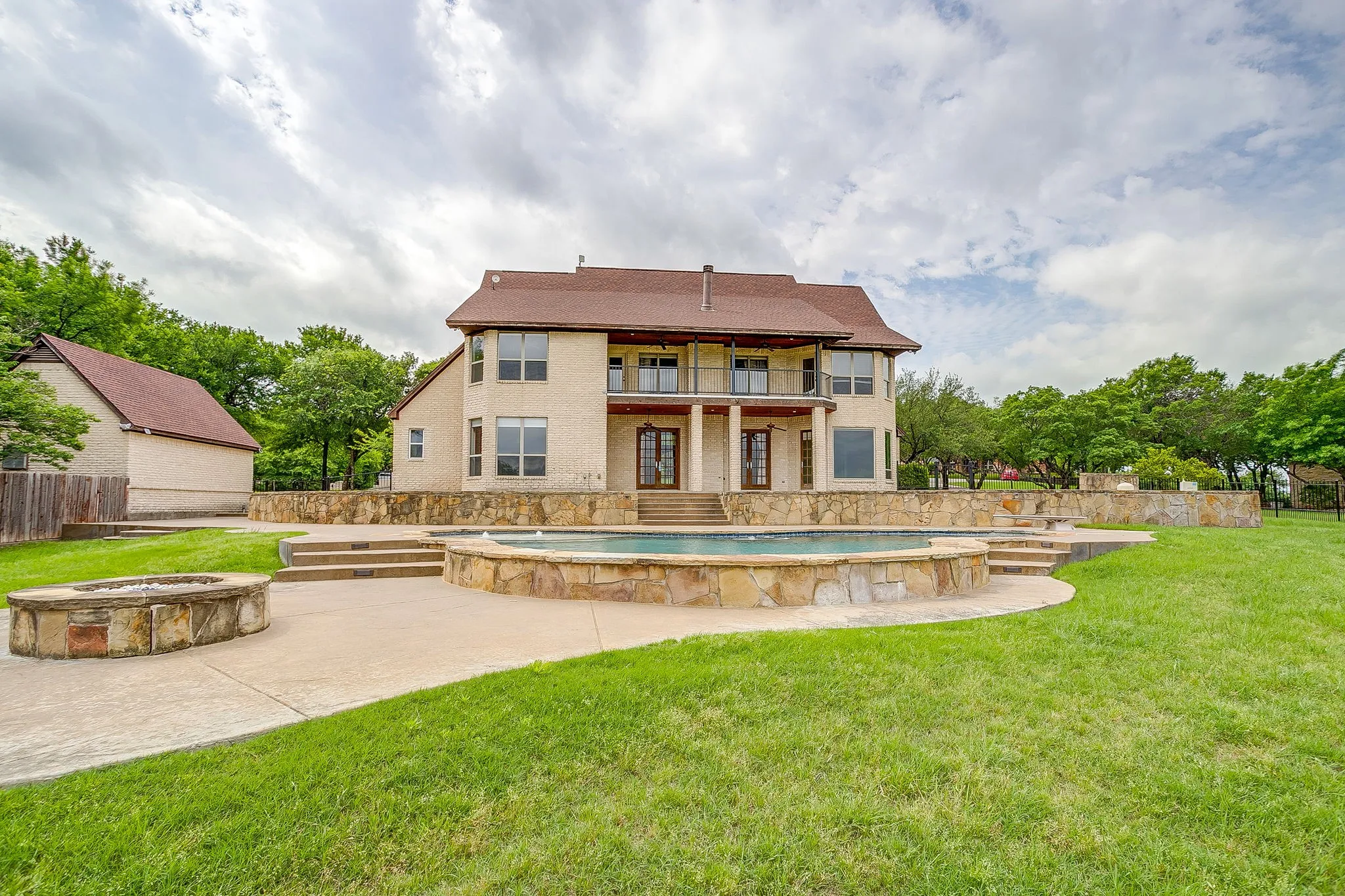 The property features a spacious rear exterior with a swimming pool, a fire pit, and extensive lawn space