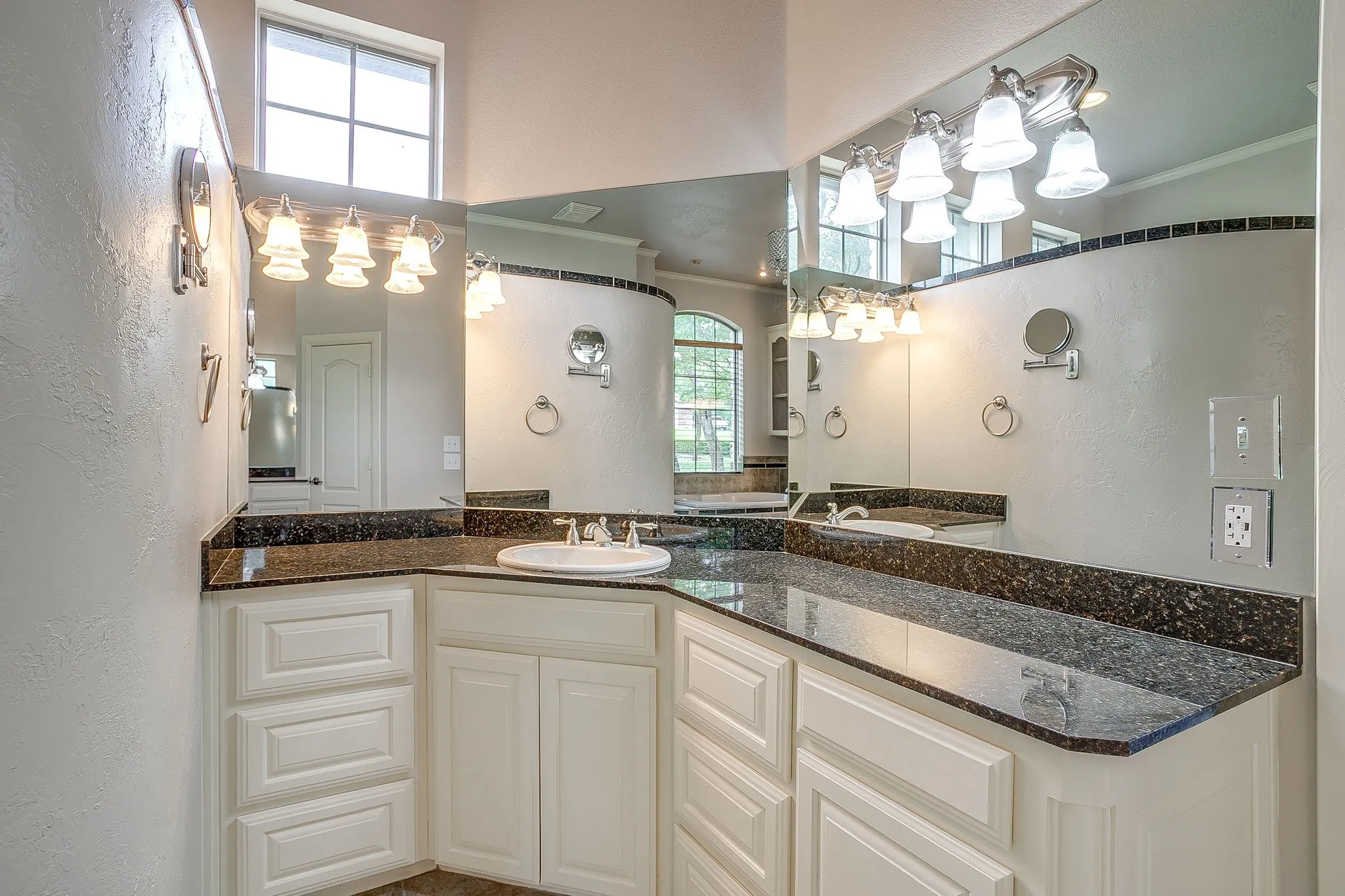Bathroom vanity featuring a dark granite countertop, a white porcelain sink, and white cabinetry