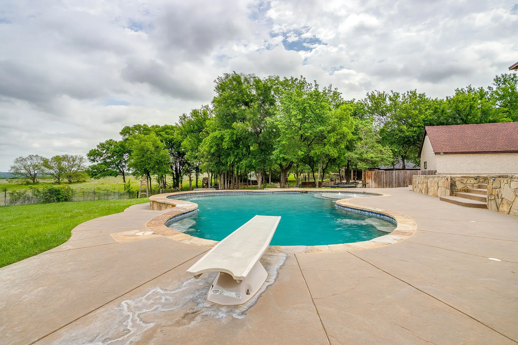 The property features an outdoor swimming pool with a diving board, surrounded by a concrete patio