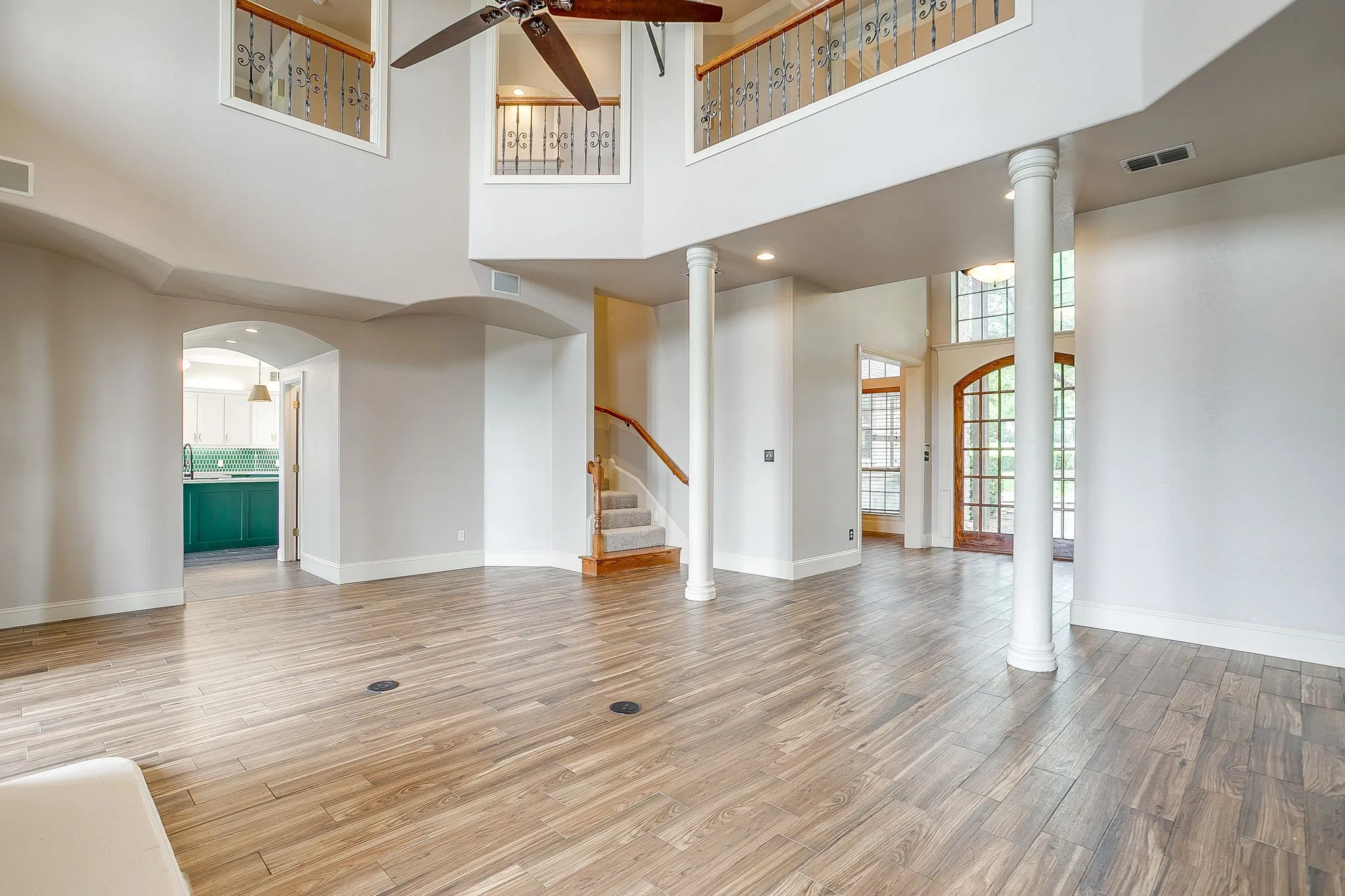 This spacious living area features high ceilings, hardwood flooring, and decorative columns