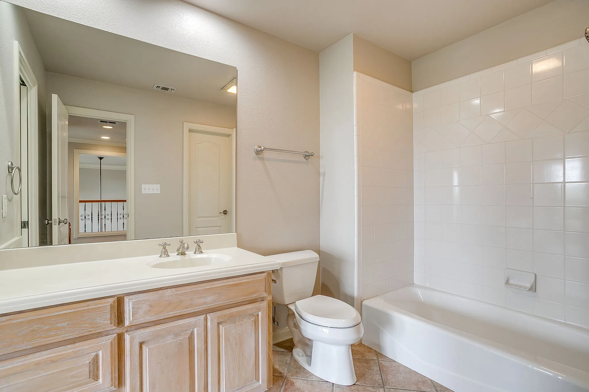 Bathroom featuring a vanity with a light-colored countertop and a mirror, a toilet, and a bathtub with white tile surround