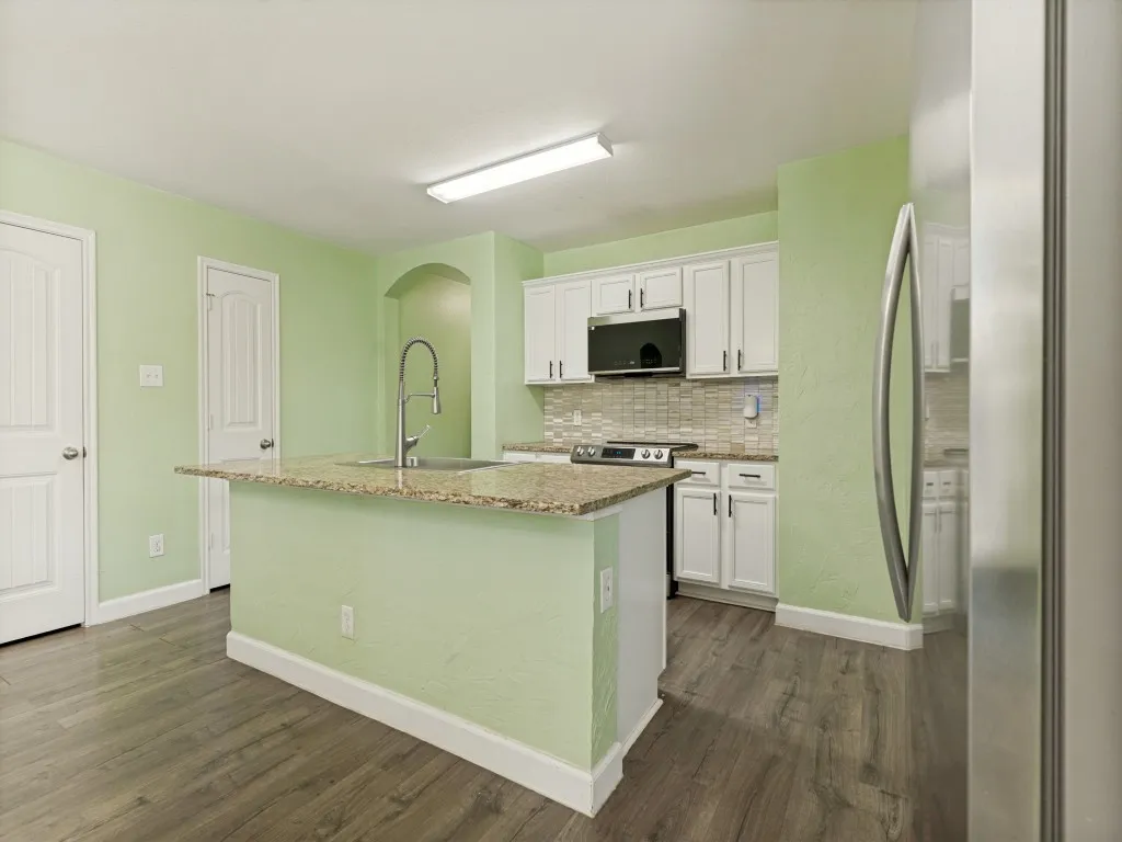 Oversized granite island anchors this stylish kitchen, offering prep space, seating, and effortless connection to the living areas