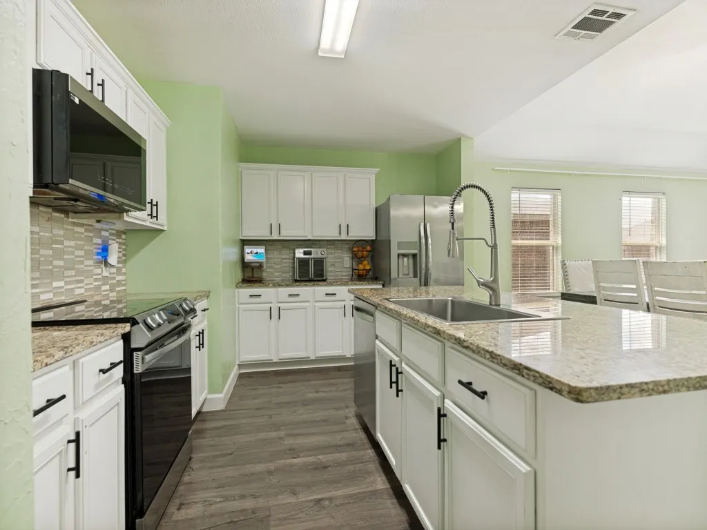 Bright, open kitchen with granite island, abundant storage, and seamless entertaining flow.

