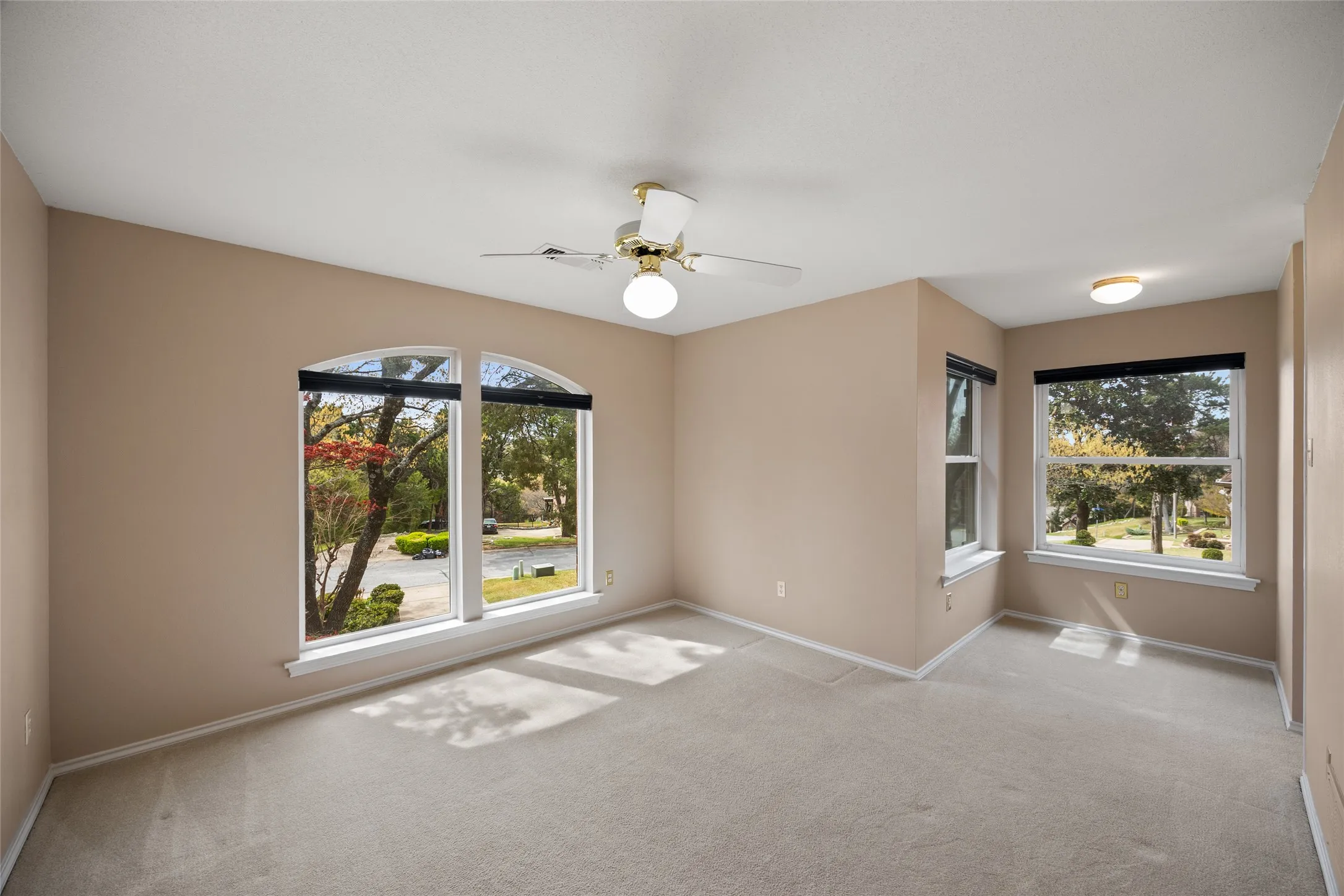 Unfurnished bedroom on second floor featuring a ceiling fan, light colored carpet, and healthy amount of natural light