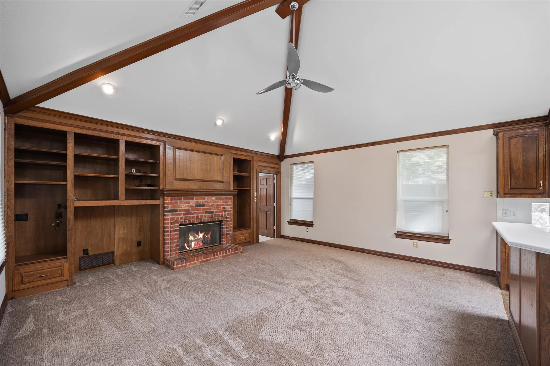 Unfurnished living room featuring lofted ceiling, ceiling fan, light colored carpet, a fireplace, and built in features