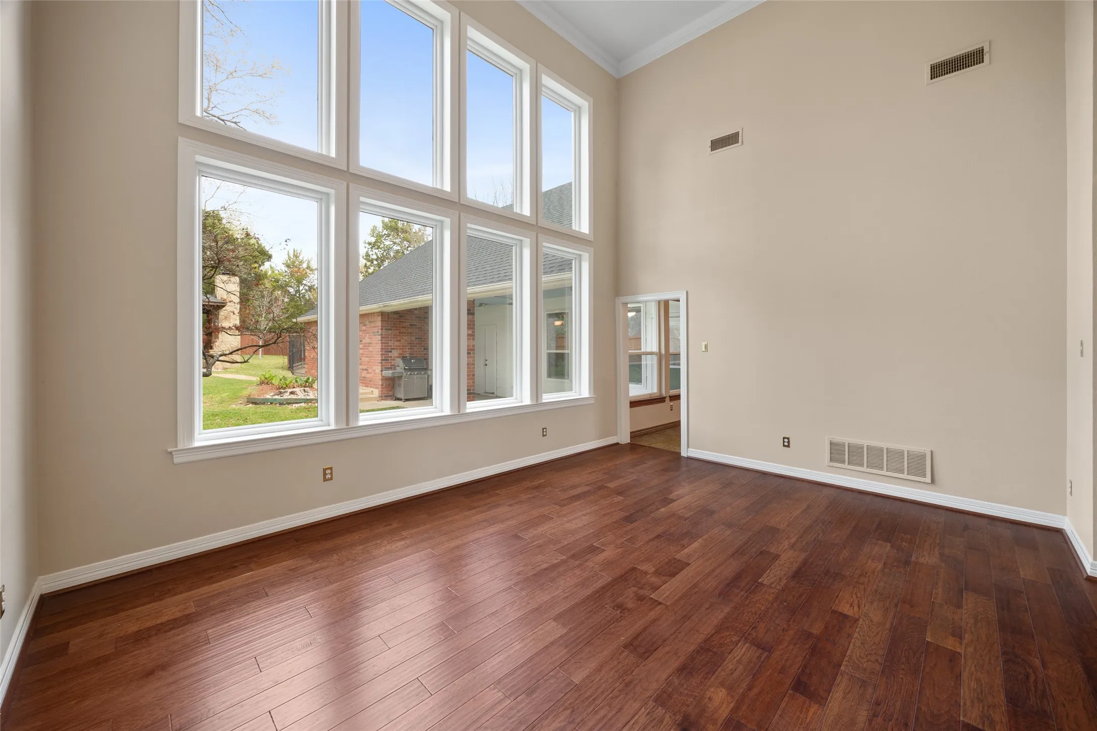 Unfurnished living room with a high ceiling, dark wood finished floors, and crown molding