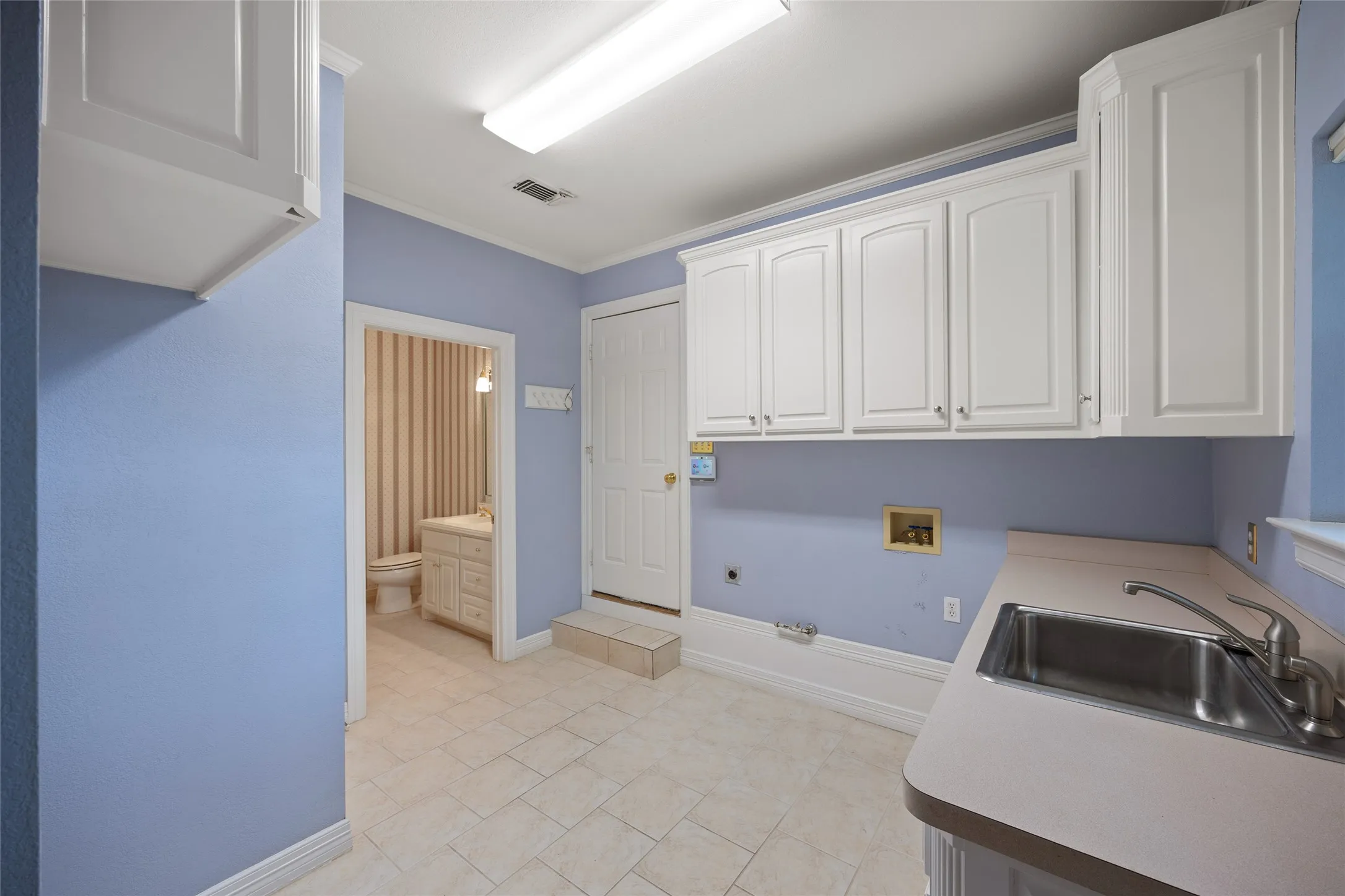 Laundry area with hookup for a washing machine, electric dryer hookup, gas dryer hookup, ornamental molding, and cabinet space