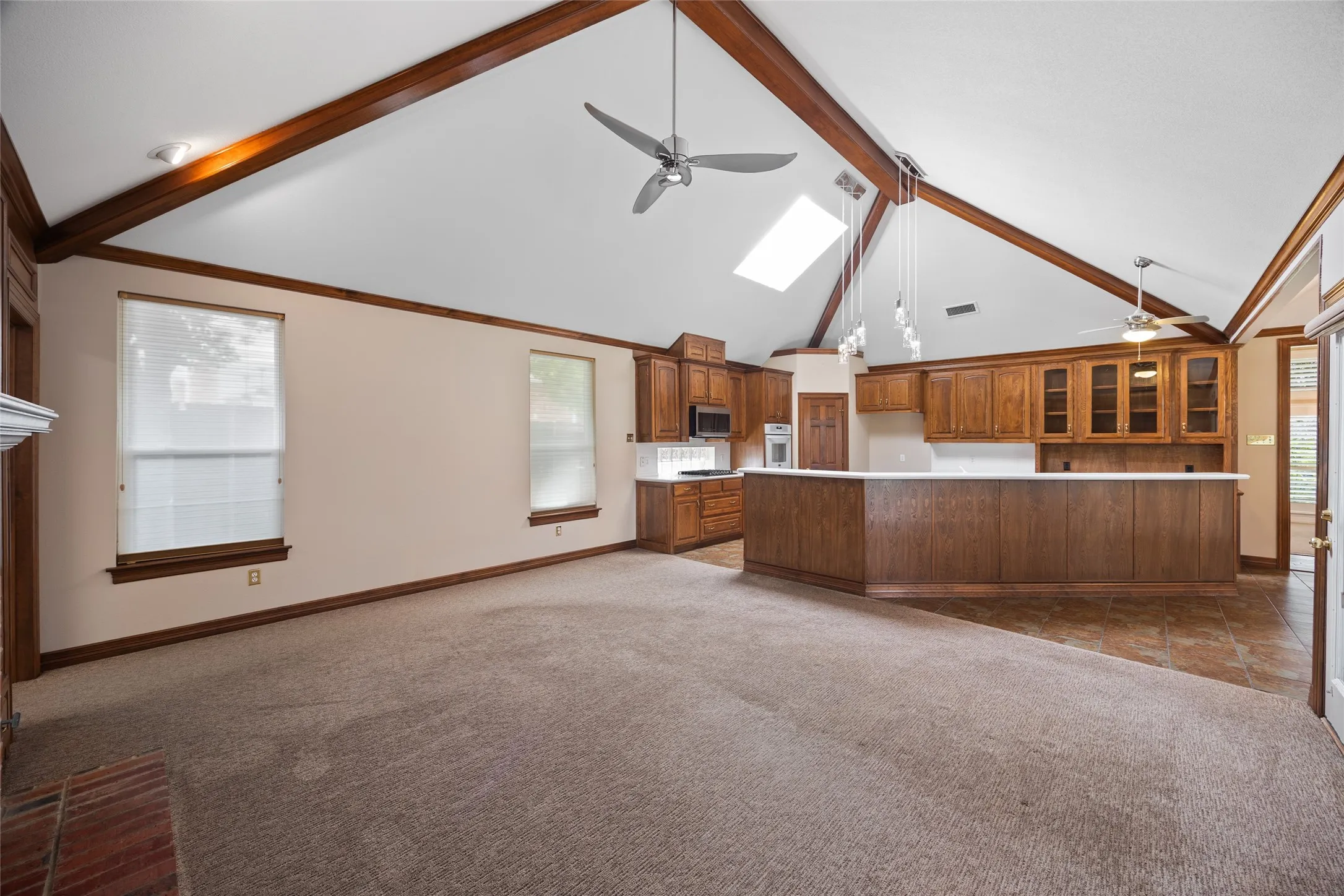 Kitchen with open floor plan, a ceiling fan, a kitchen island, wood finish cabinets, and lofted ceiling