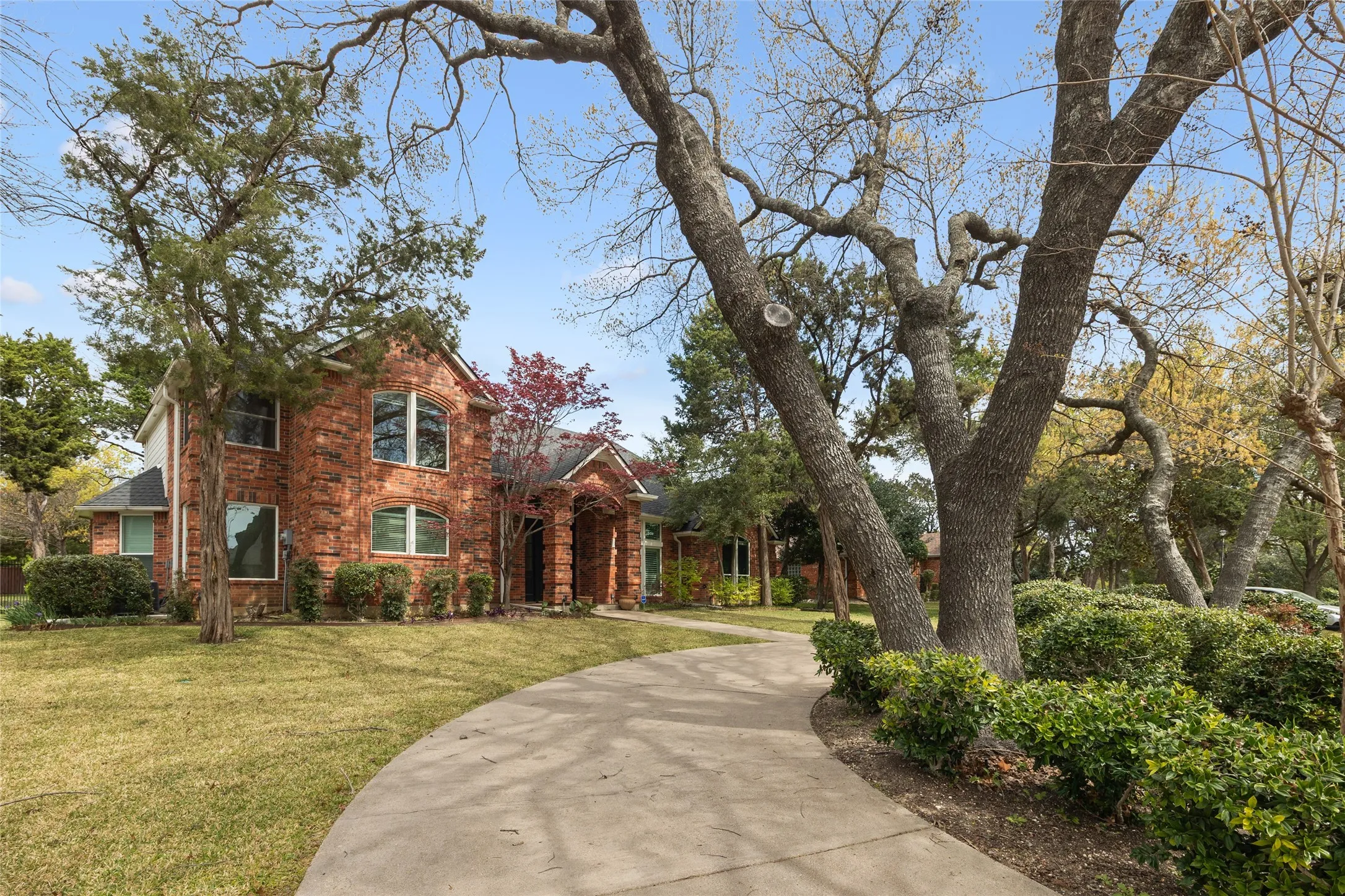 Traditional-style house with a front lawn, driveway, and brick siding