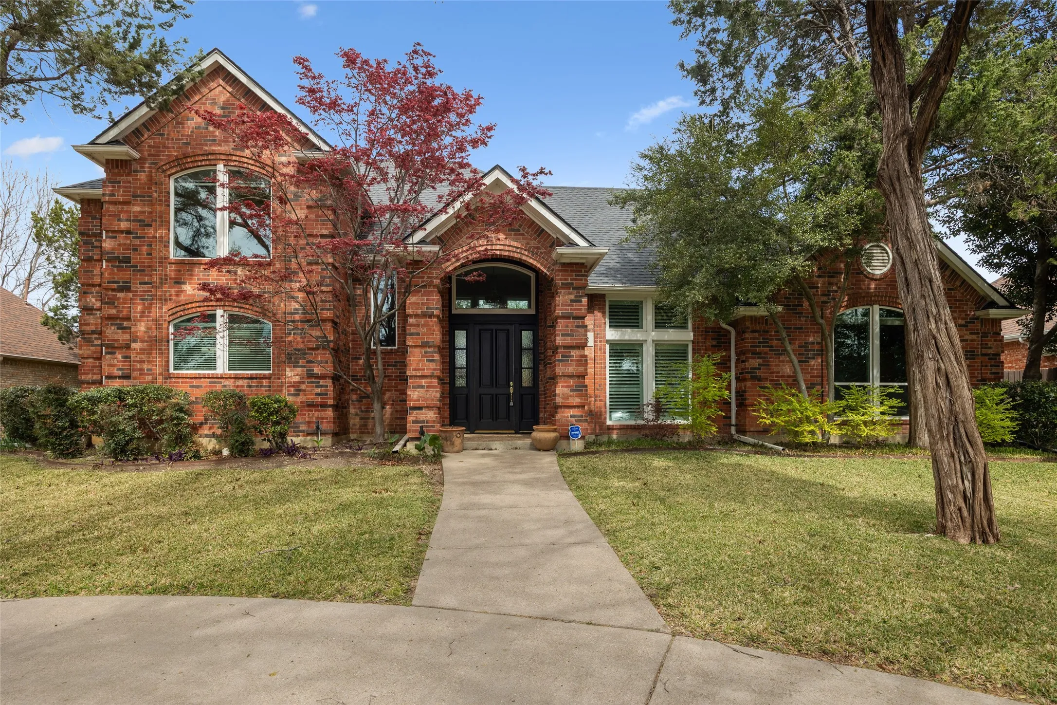 Traditional home with brick siding, a front lawn, and roof with shingles