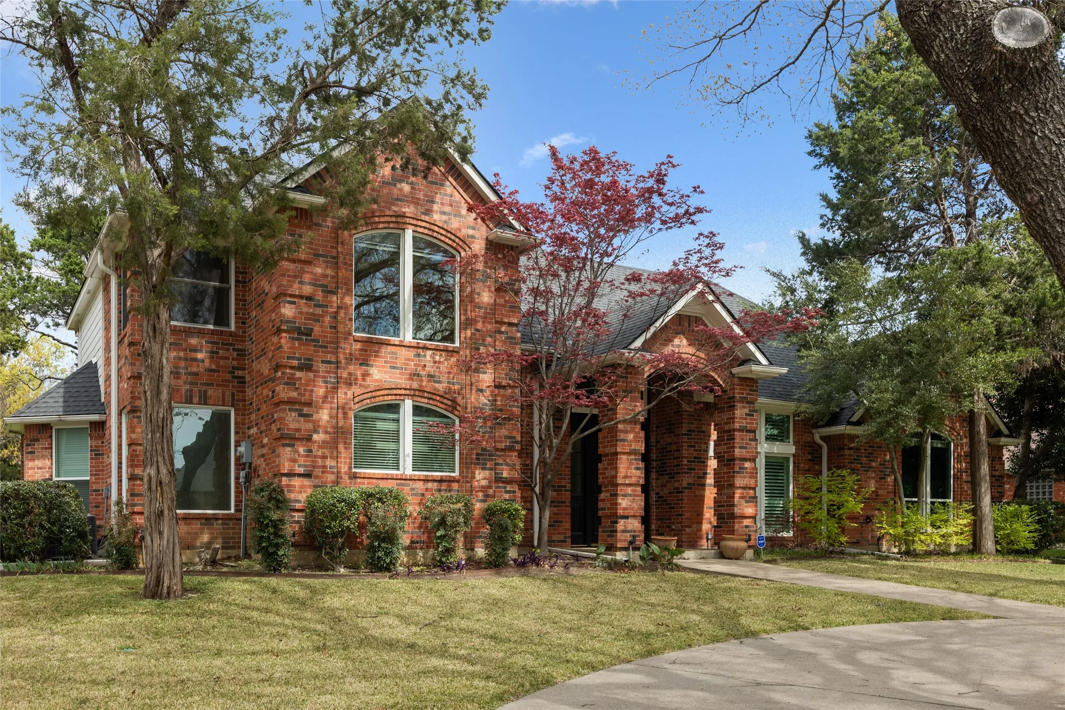 Traditional home featuring a front yard and brick siding