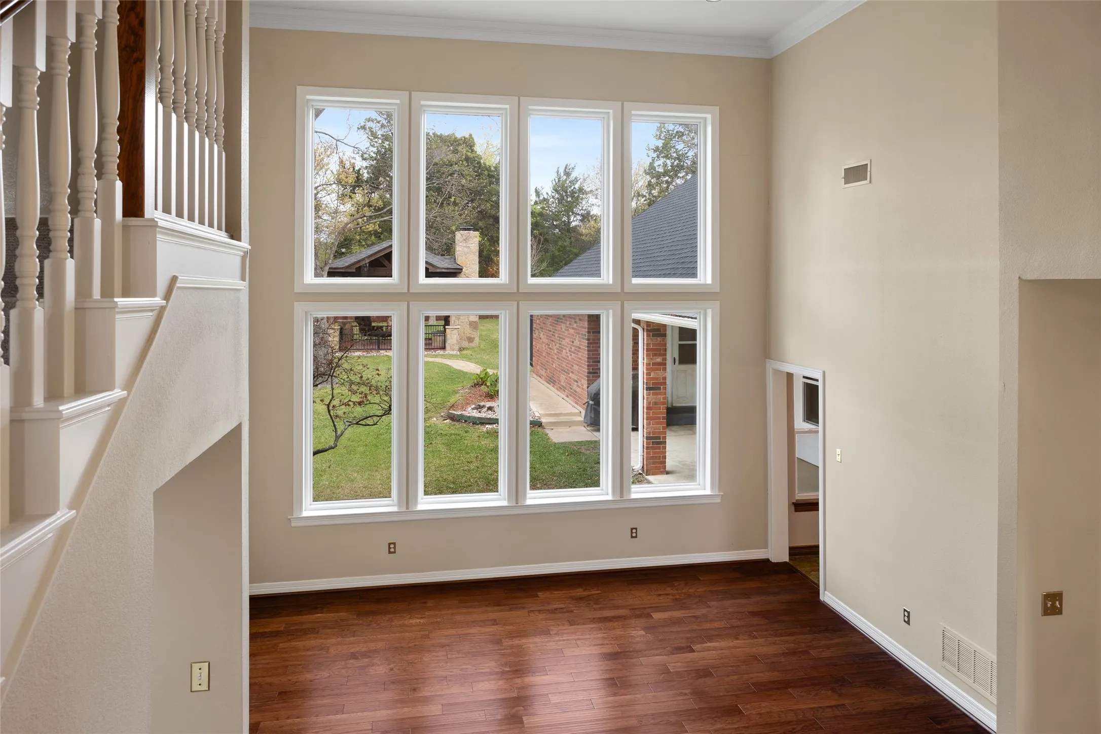 Unfurnished living room with dark wood-style flooring, crown molding, and a high ceiling