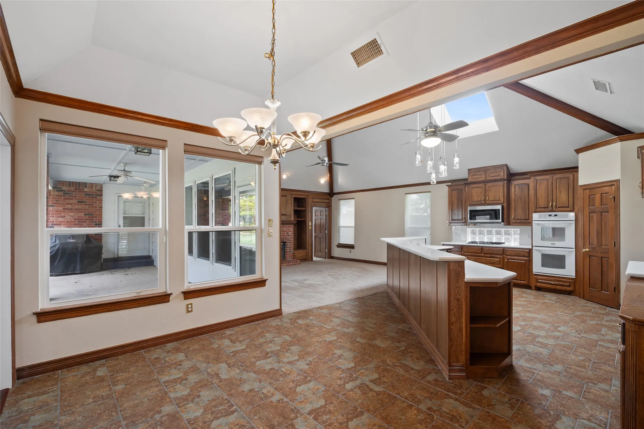 (Unfurnished) Breakfast area featuring ceiling fan, lofted ceiling, dark stone finish flooring, light fixtures and ornamental molding, great open space with wonderful views of the backyard spaces.