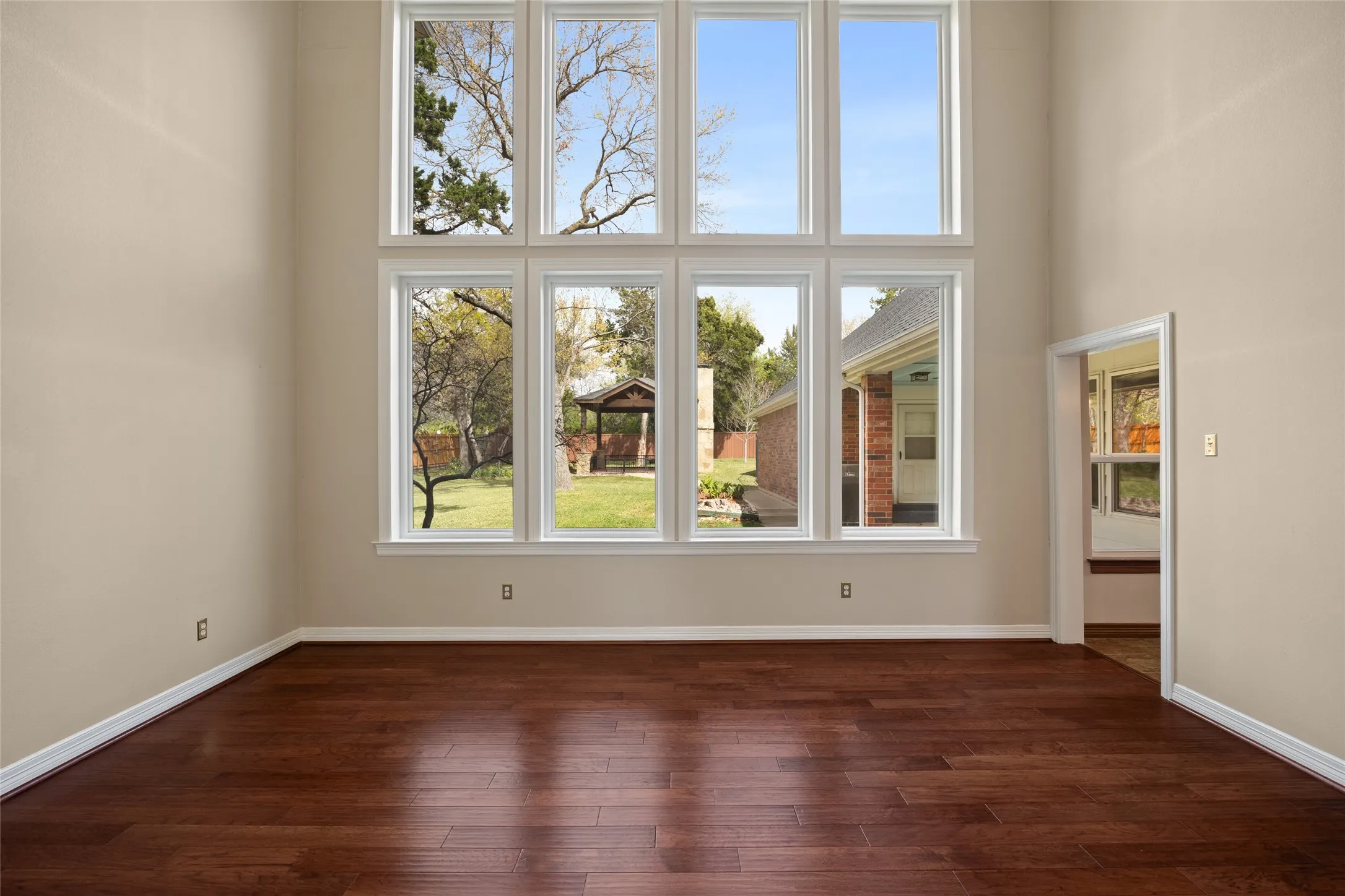 Great room unfurnished with a high ceiling, dark wood finished floors, and plenty of natural light.  generous space for family gatherings