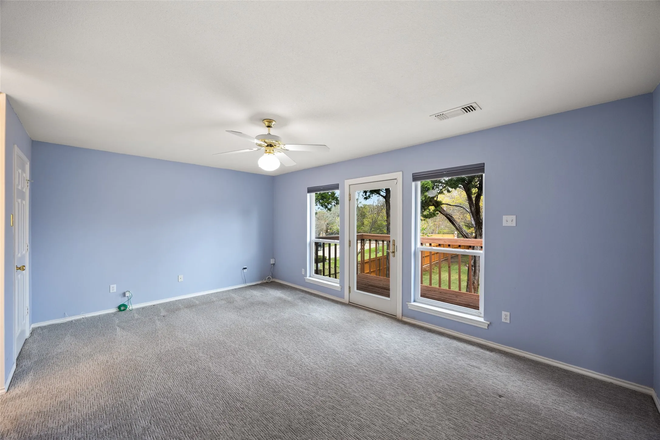 upstairs bedroom back of home with access to balcony with wonderful views of the back yard. Carpeted empty room with a ceiling fan and baseboards