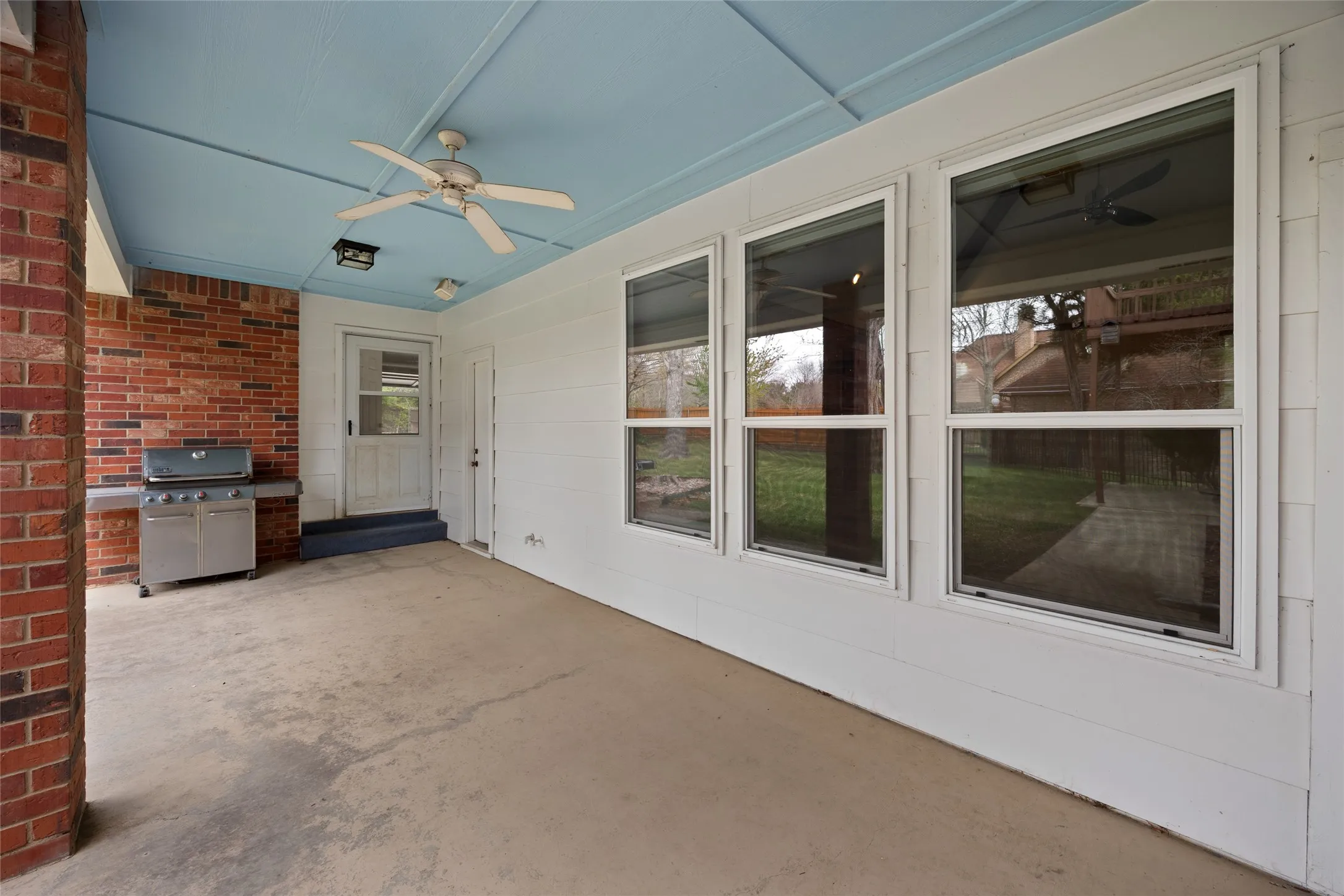 View of second patio outside of living kitchen area featuring a ceiling fan and area for grilling