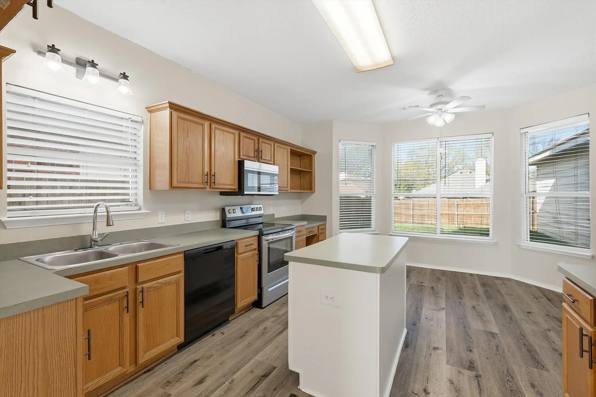 Kitchen featuring stainless steel appliances, a ceiling fan, a center island, and light countertops