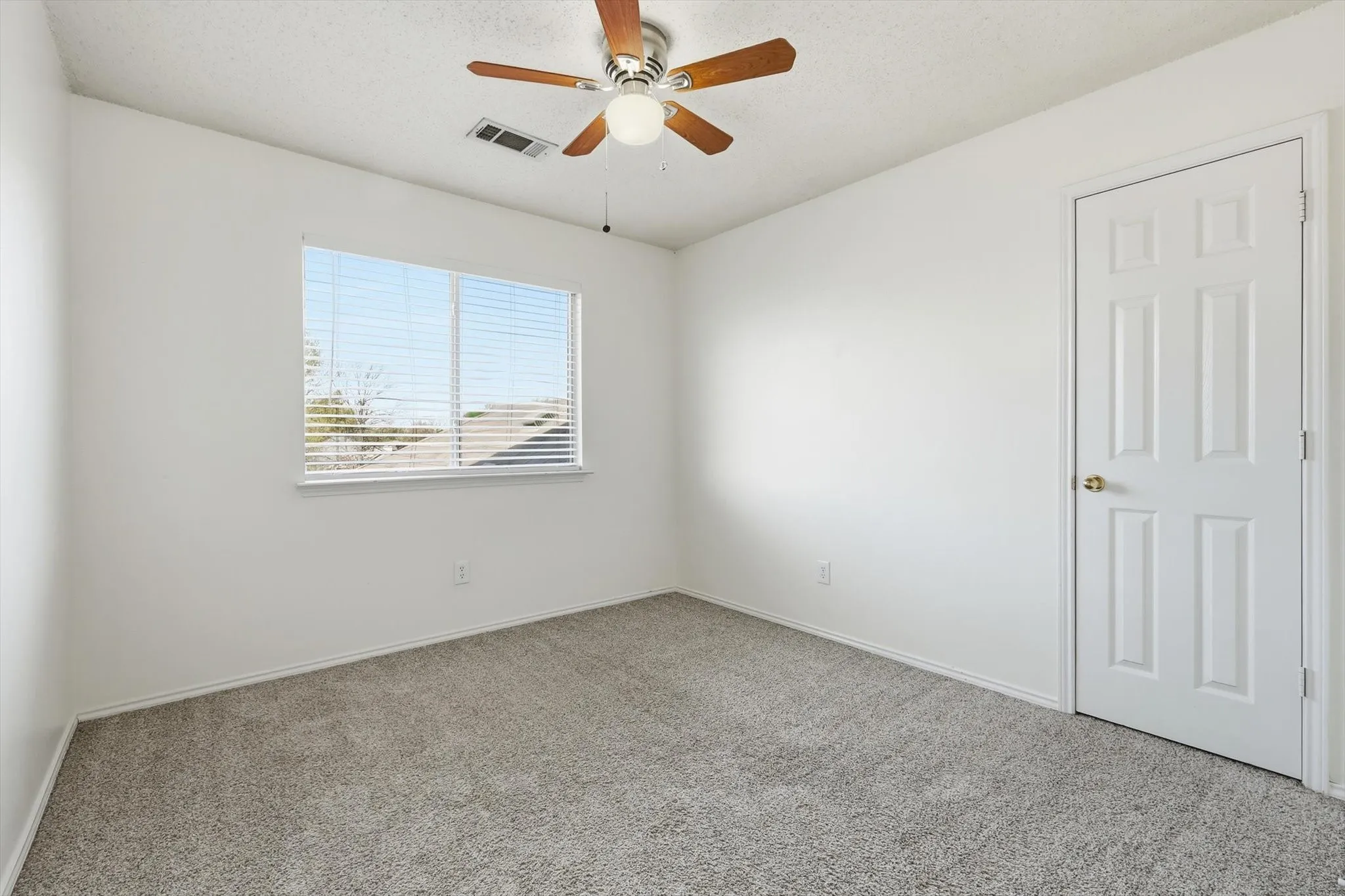 Spare room featuring carpet, a ceiling fan, and a textured ceiling