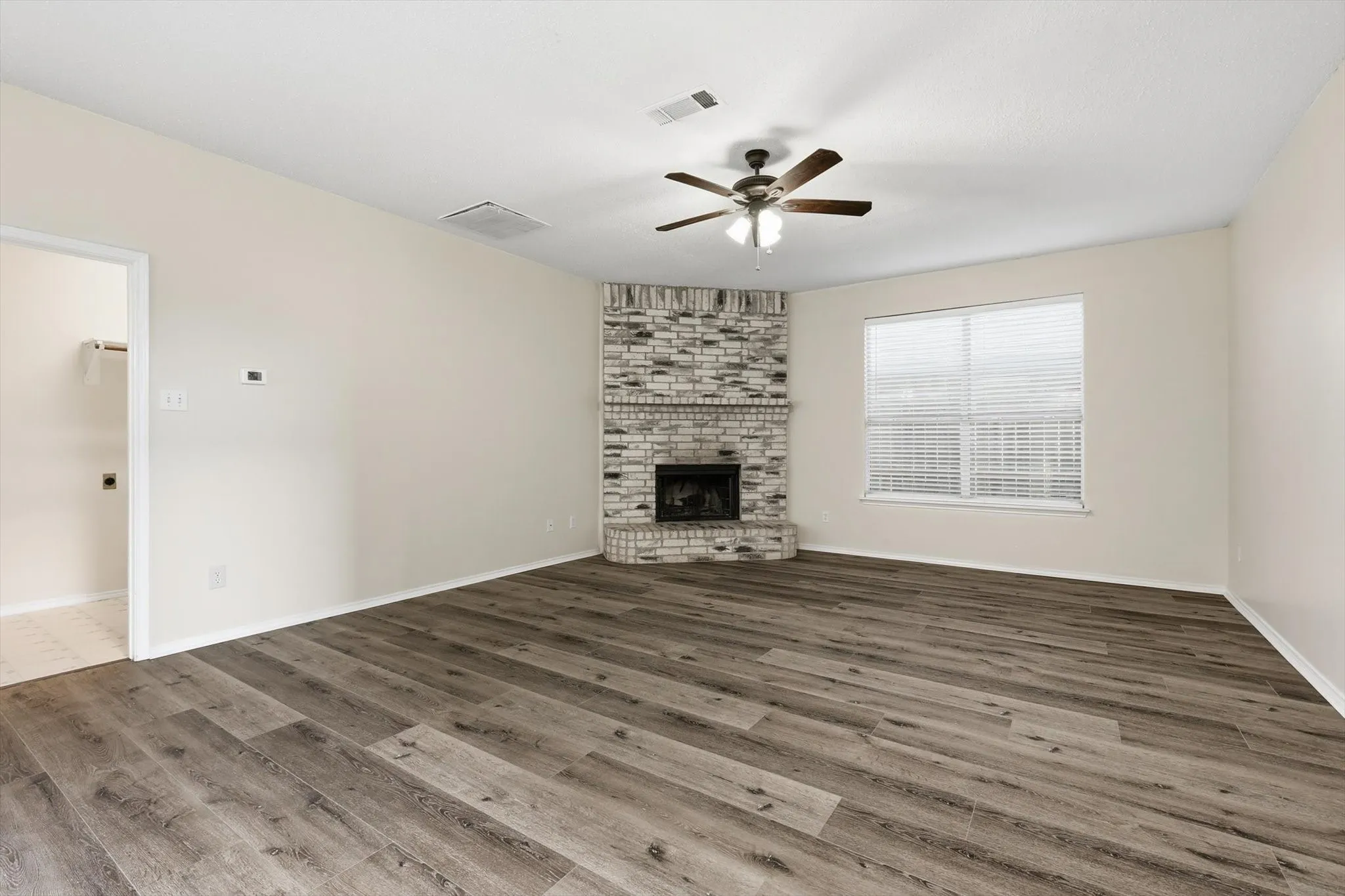 Unfurnished living room with a fireplace, ceiling fan, and dark wood-style flooring