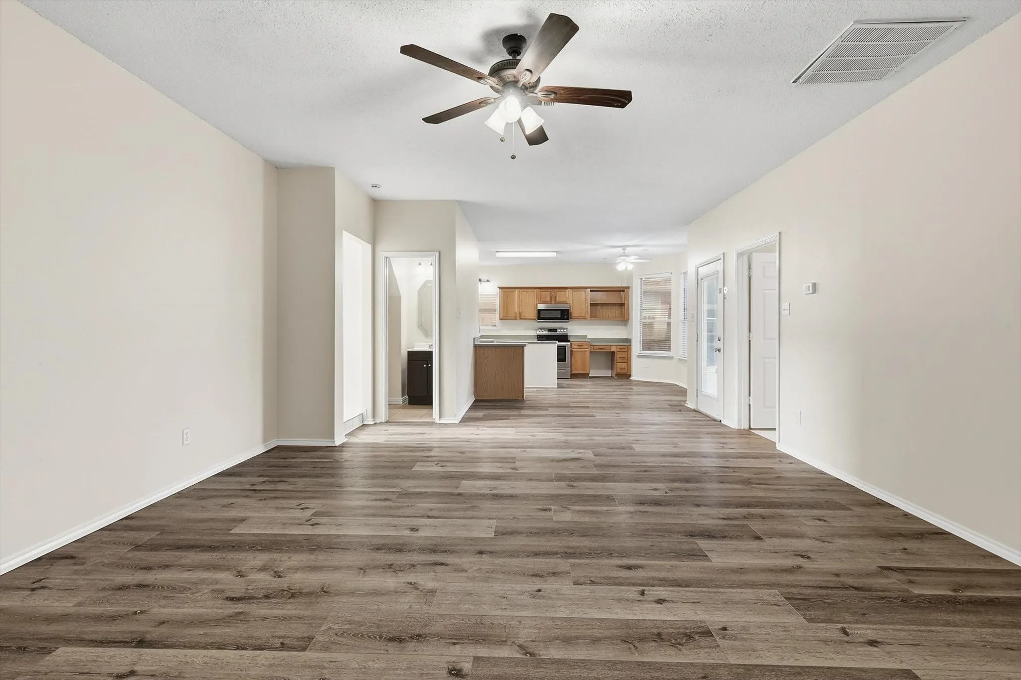 Unfurnished living room with a ceiling fan and dark wood-style flooring