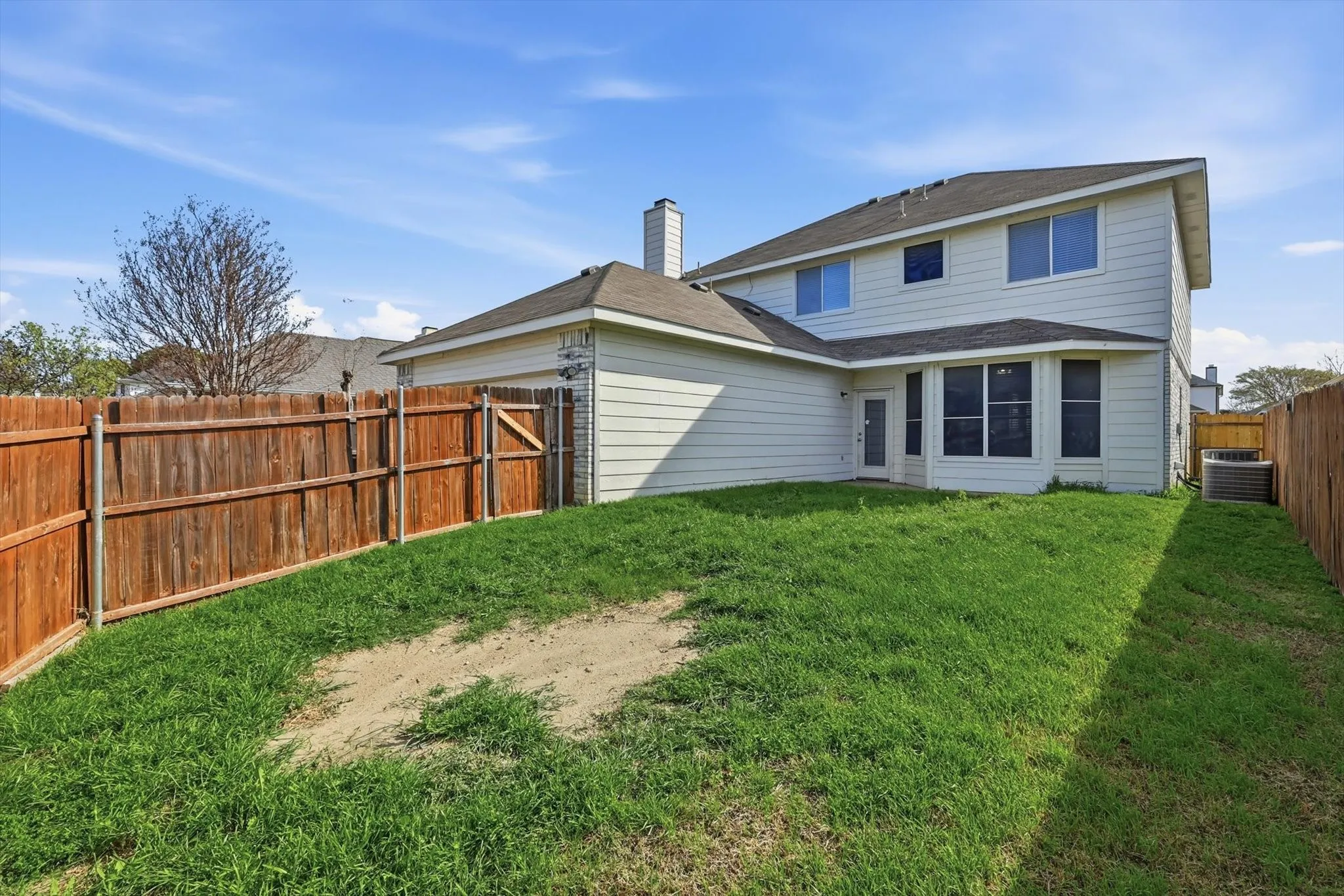 Back of property featuring a chimney, a fenced backyard, and a shingled roof