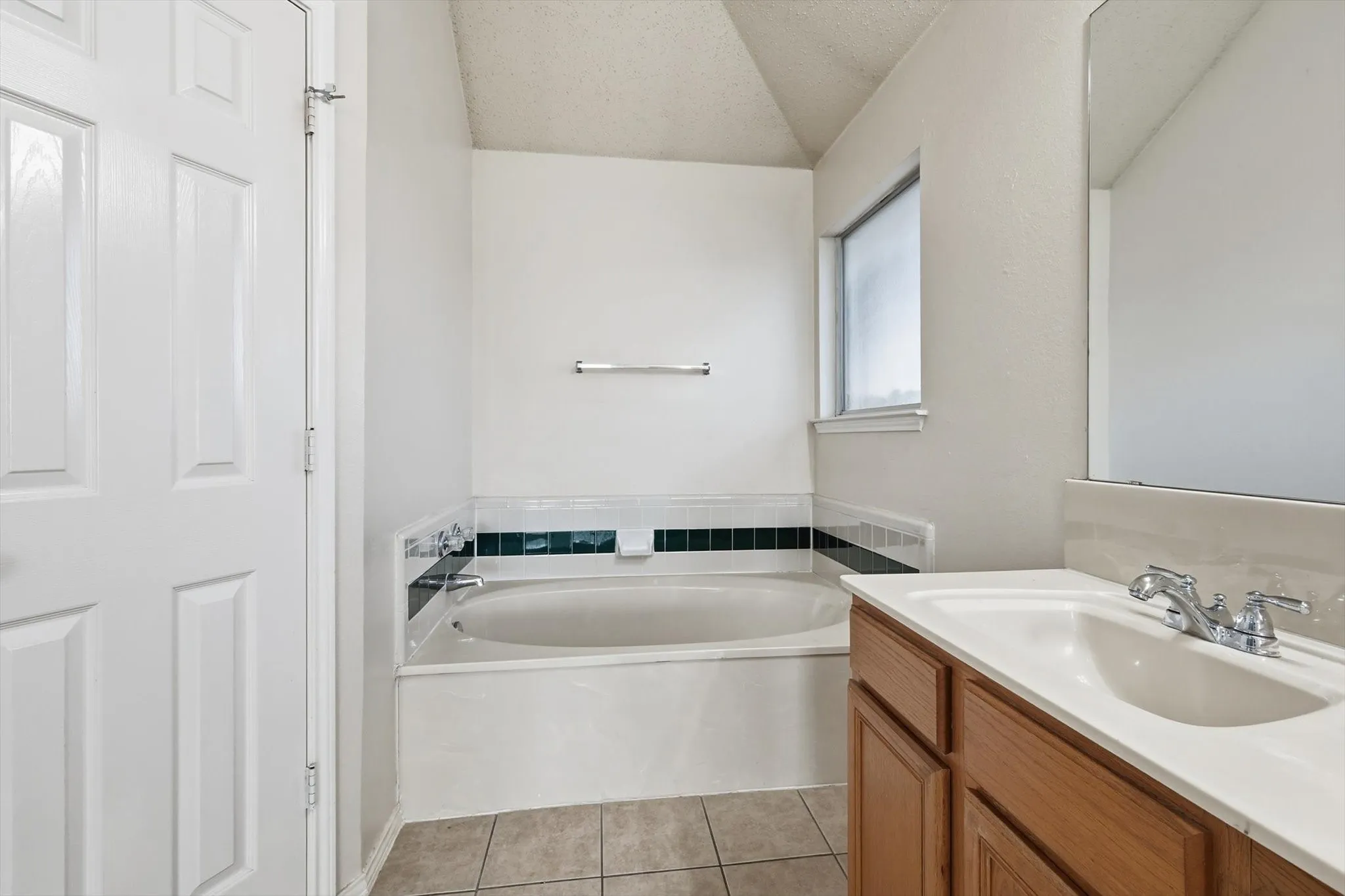 Bathroom featuring light tile patterned flooring, a bath, and vanity
