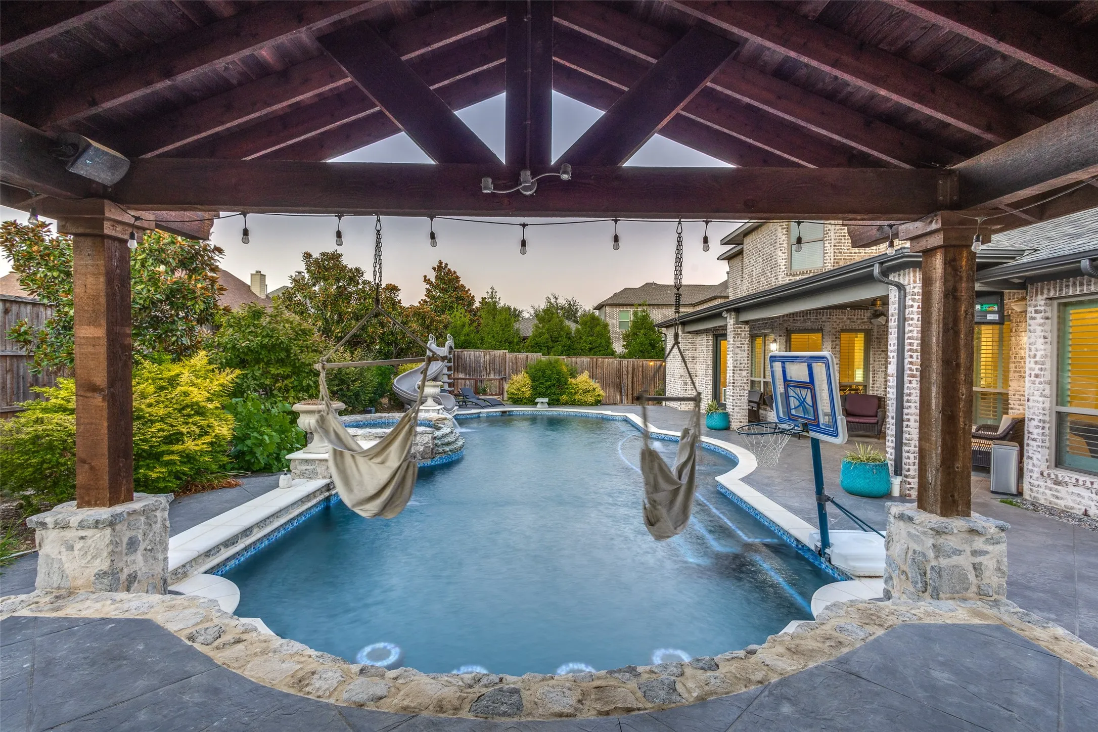 Pool at dusk featuring a fenced backyard, a patio area, a ceiling fan, and a gazebo