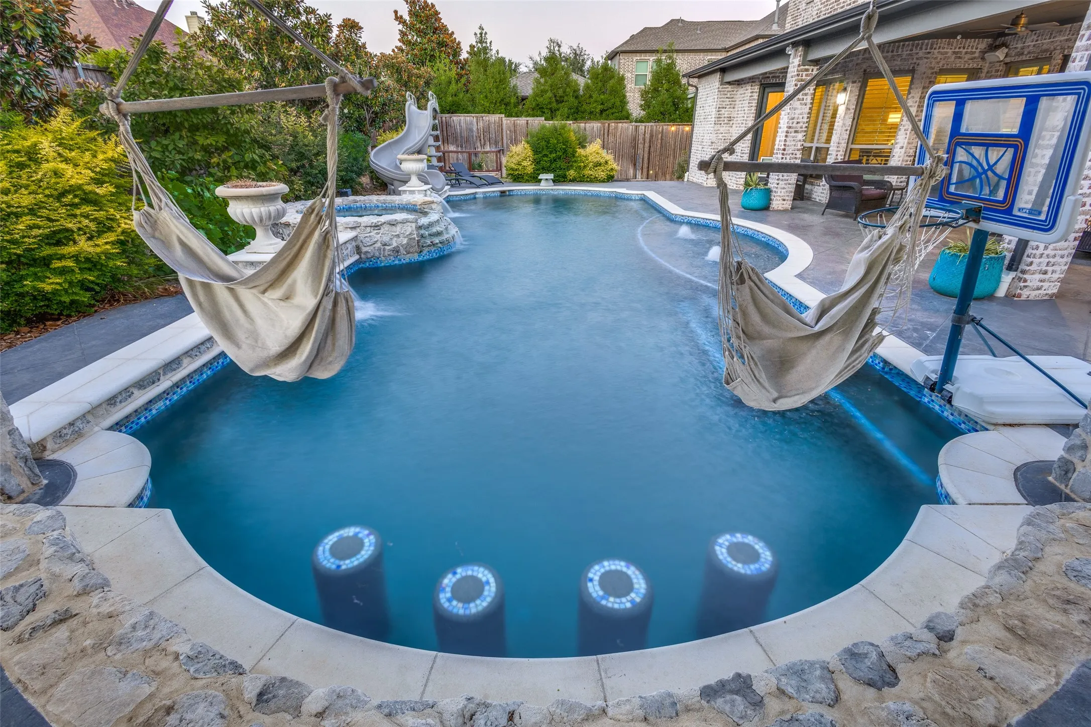 Pool at dusk with a water slide and swim up bar stools