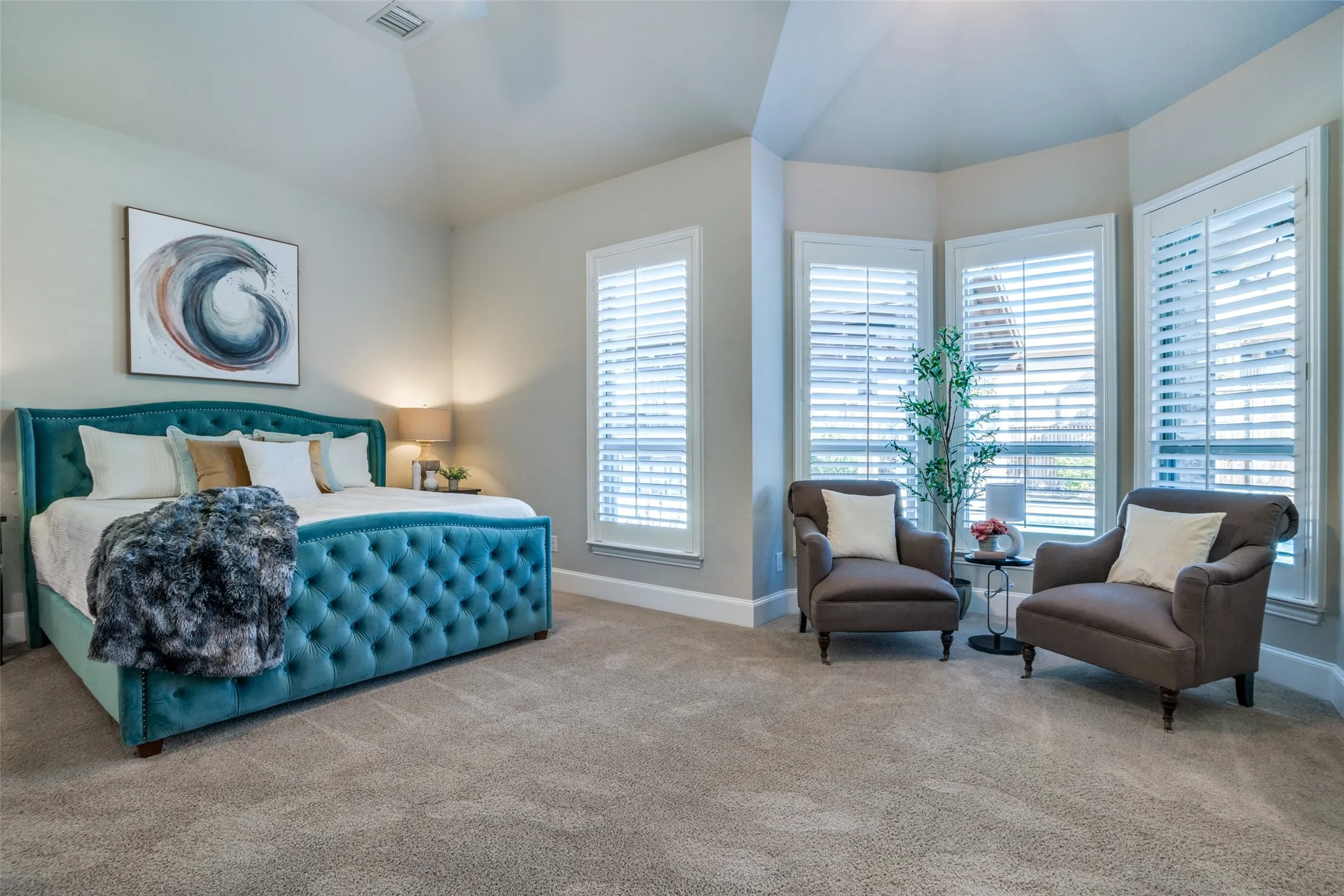 Big primary bedroom featuring lofted ceiling and bay window sitting area