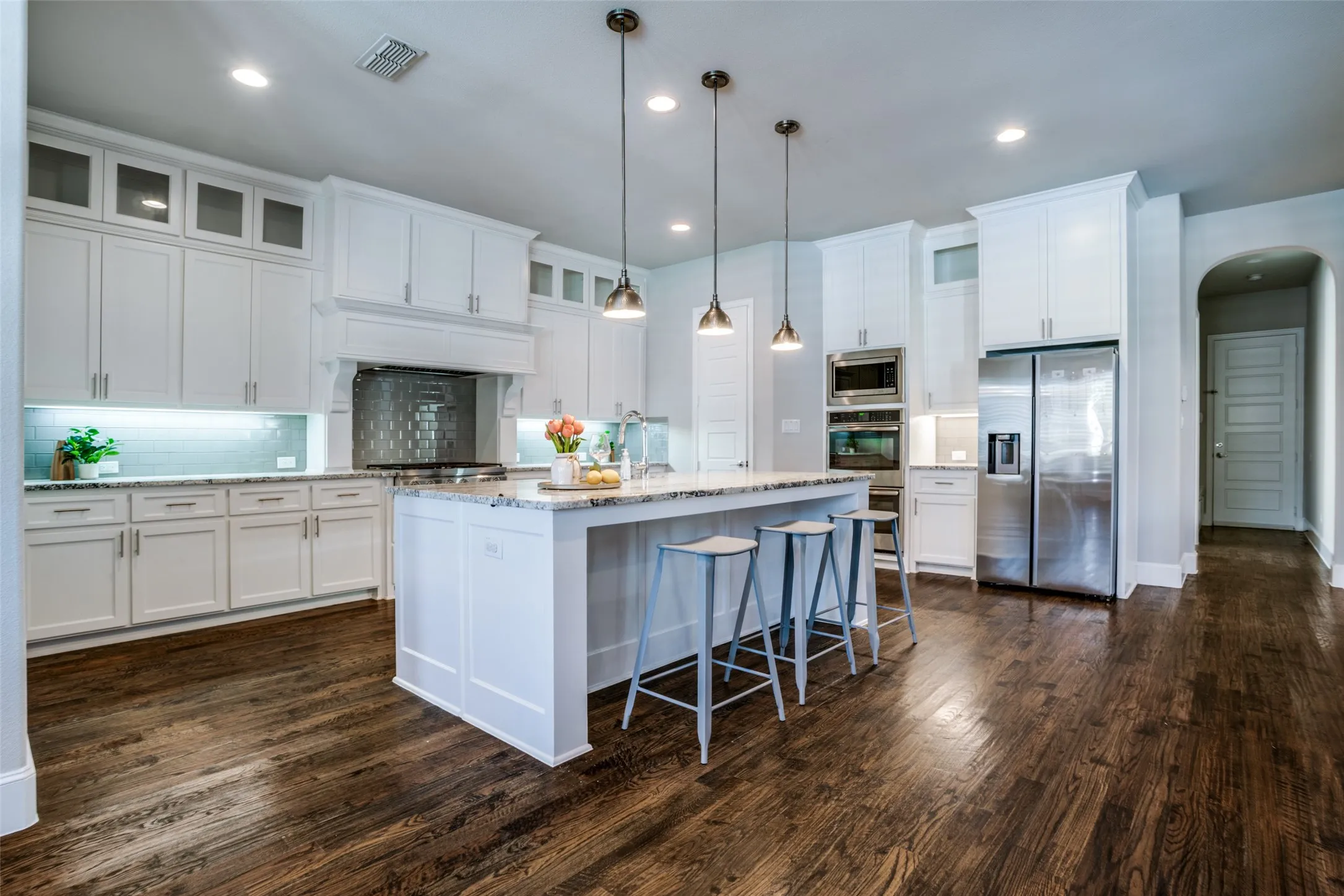 Kitchen featuring pendant lights over island and tall cabinets