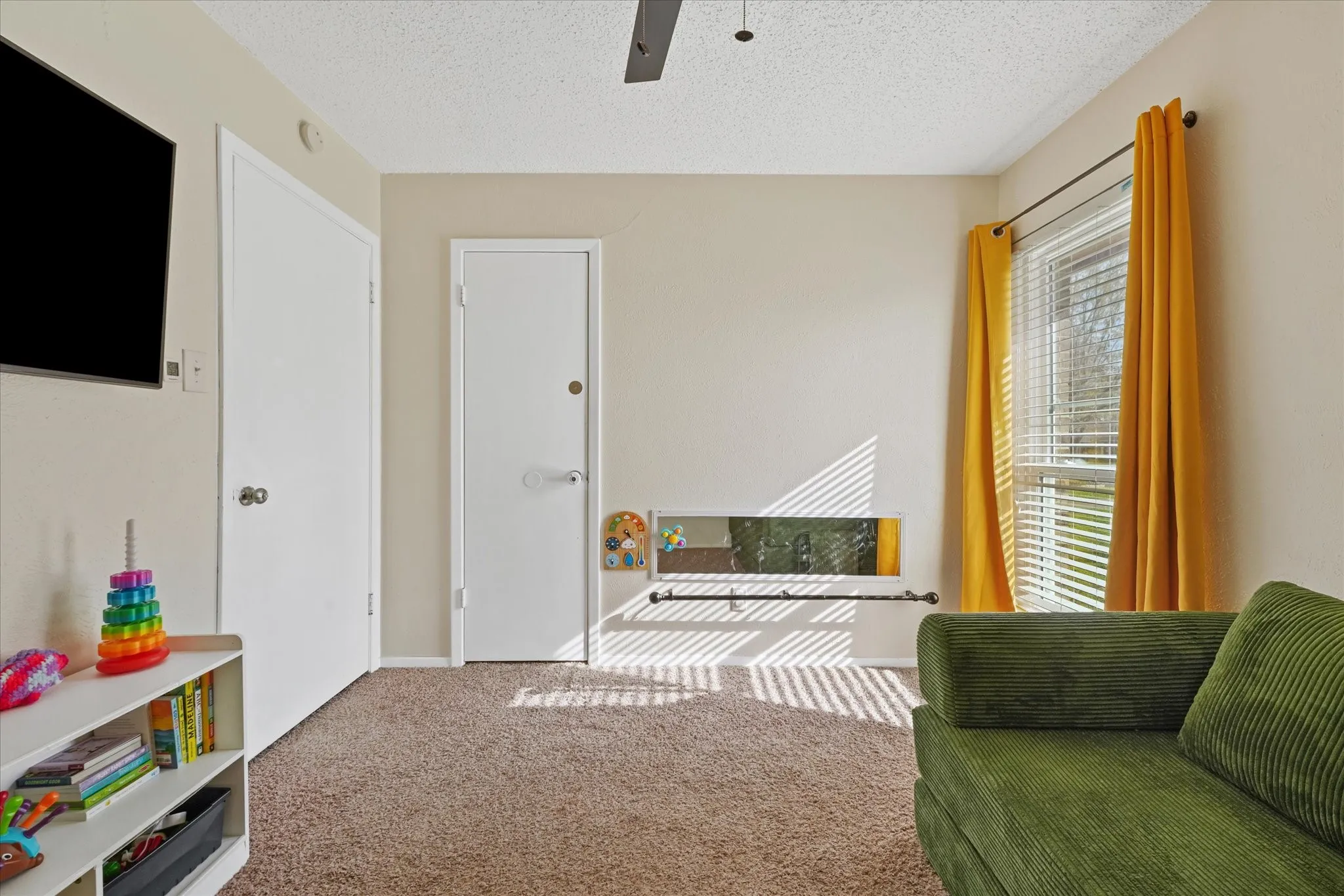 Bright secondary bedroom with large window, abundant natural light, and neutral tones—ideal for a guest room, home office, or flex space. Features soft carpet, ceiling fan, and functional layout.