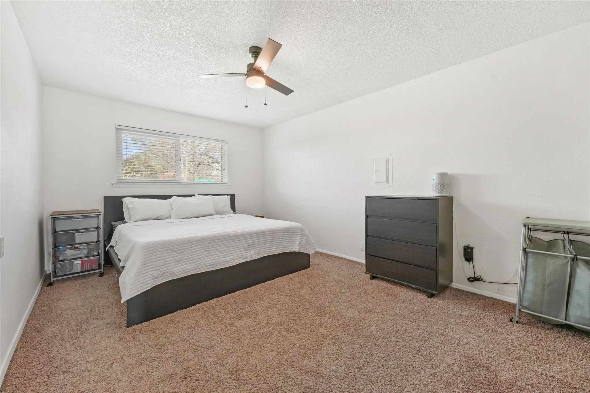 Large primary bedroom with neutral finishes, ceiling fan, and plenty of space for oversized furniture. Bright and airy with natural light—perfect for a relaxing retreat.