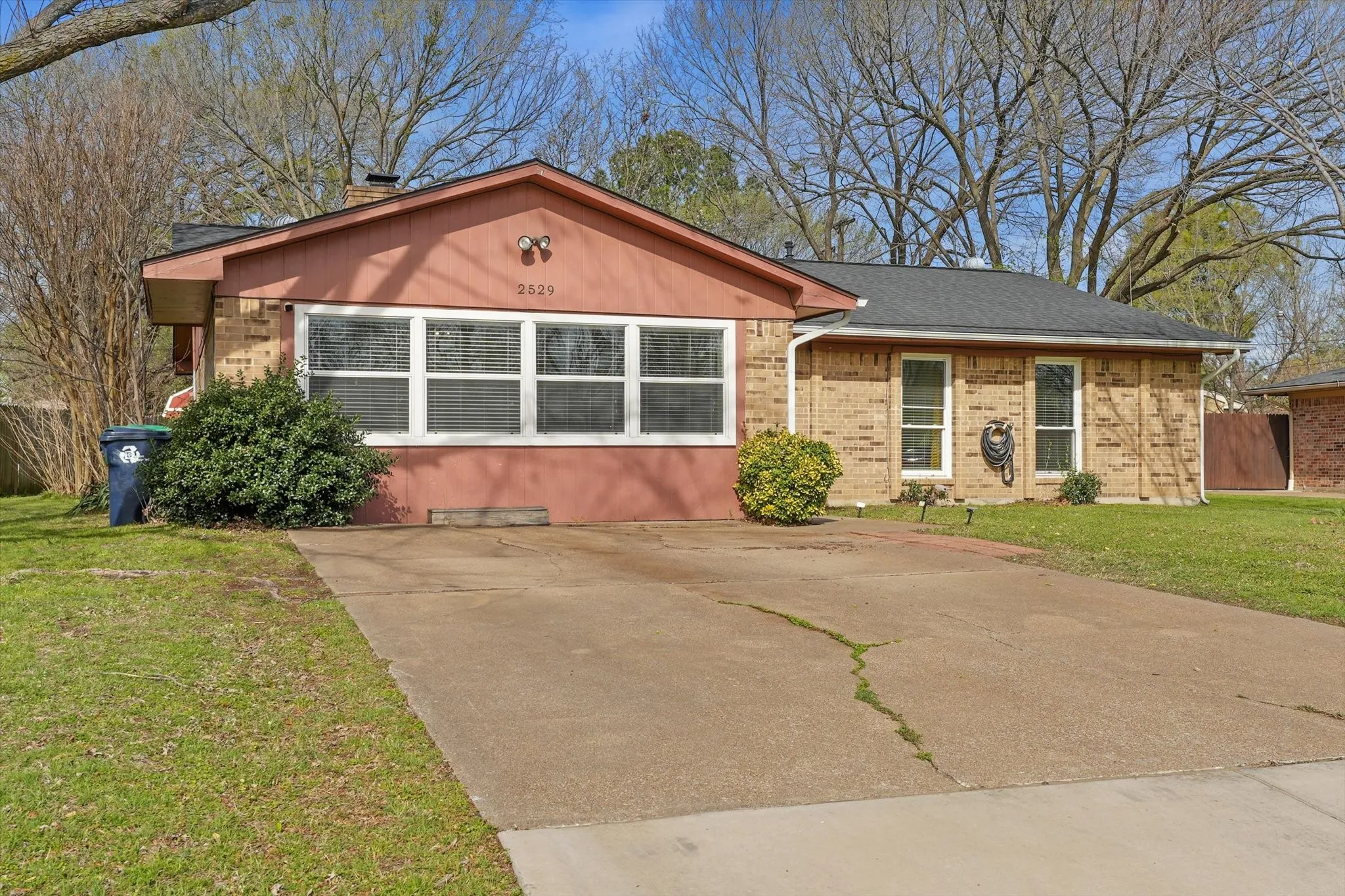 Covered front porch entry providing a Front exterior with oversized windows bringing in natural light, extended driveway parking, and easy-access layout.