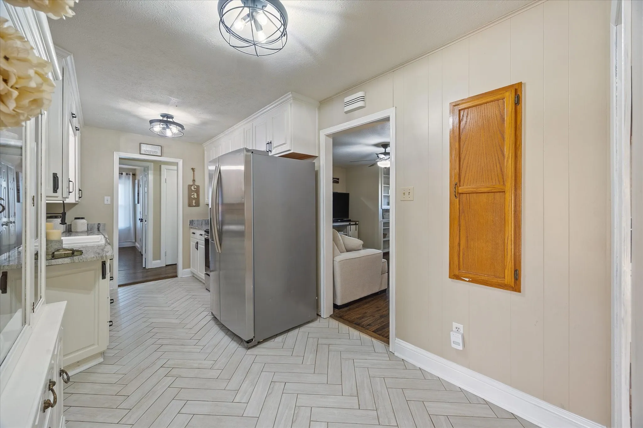 Kitchen featuring stainless steel fridge with ice dispenser, white cabinets, parquet floors, a ceiling fan, and light stone countertops