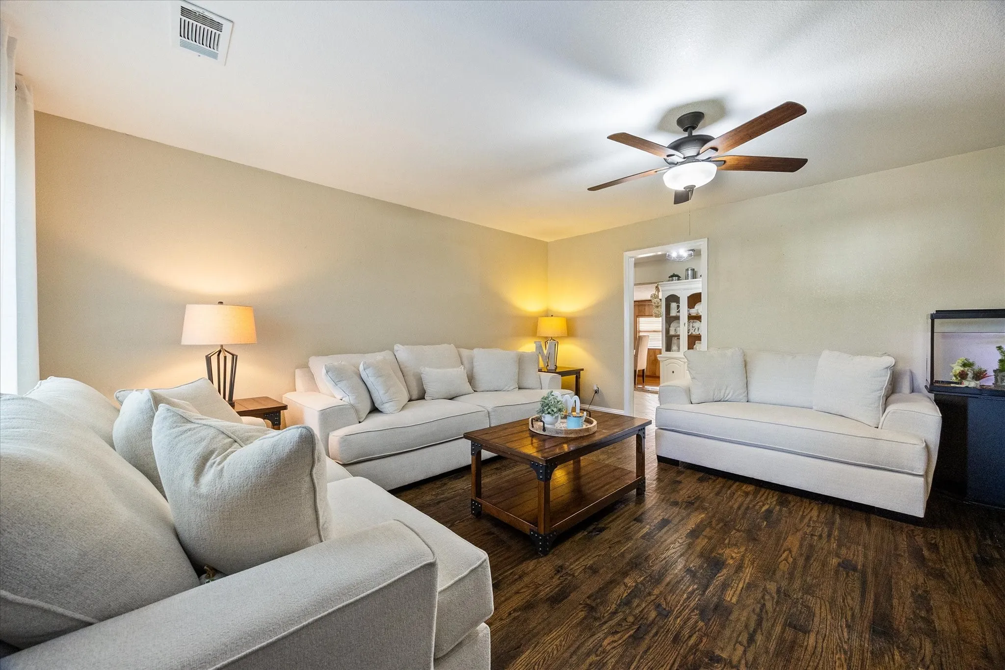 Living room featuring dark wood-style floors, ceiling fan, and built in shelves