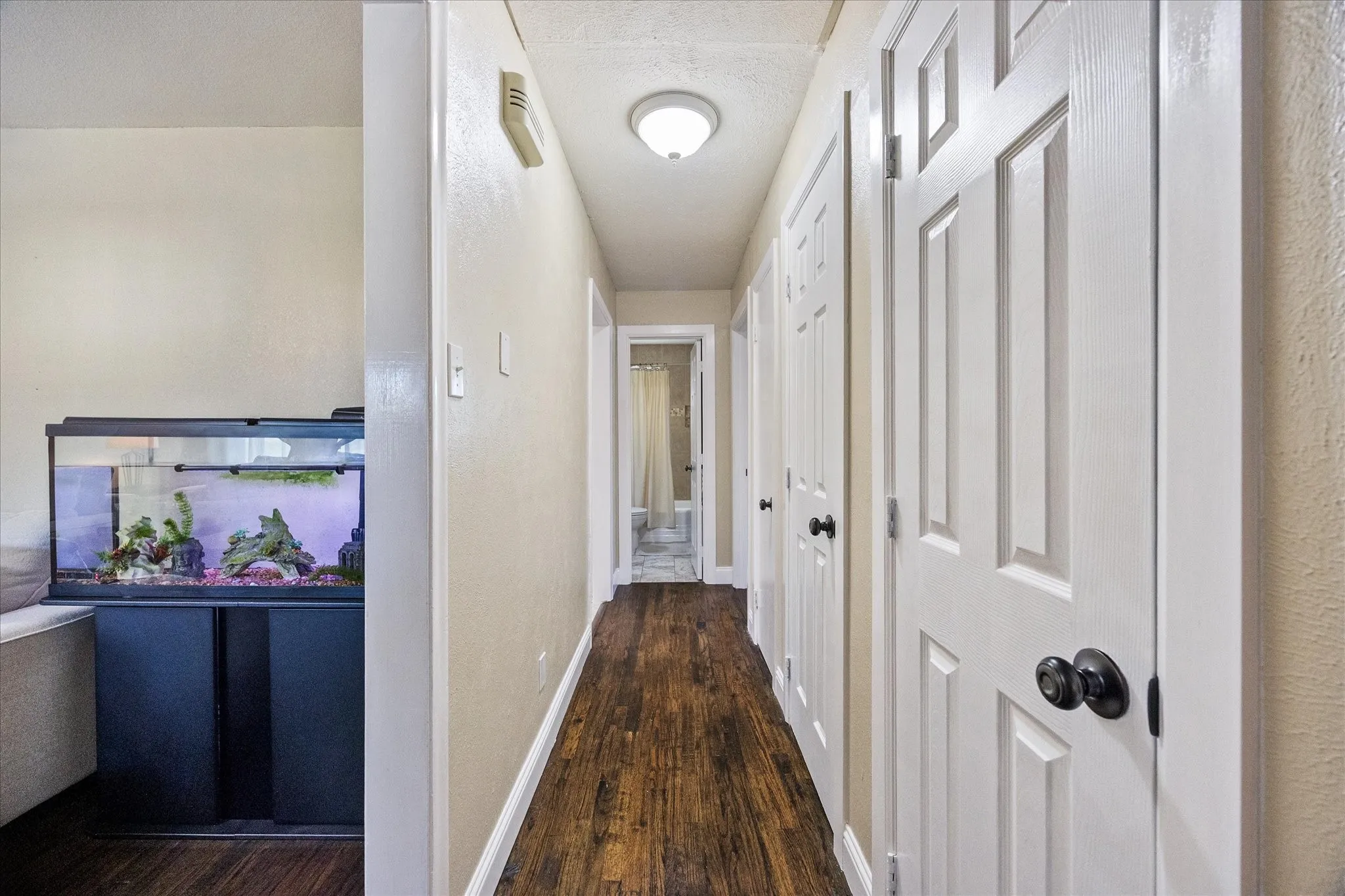 Corridor with dark wood-style flooring and a textured wall