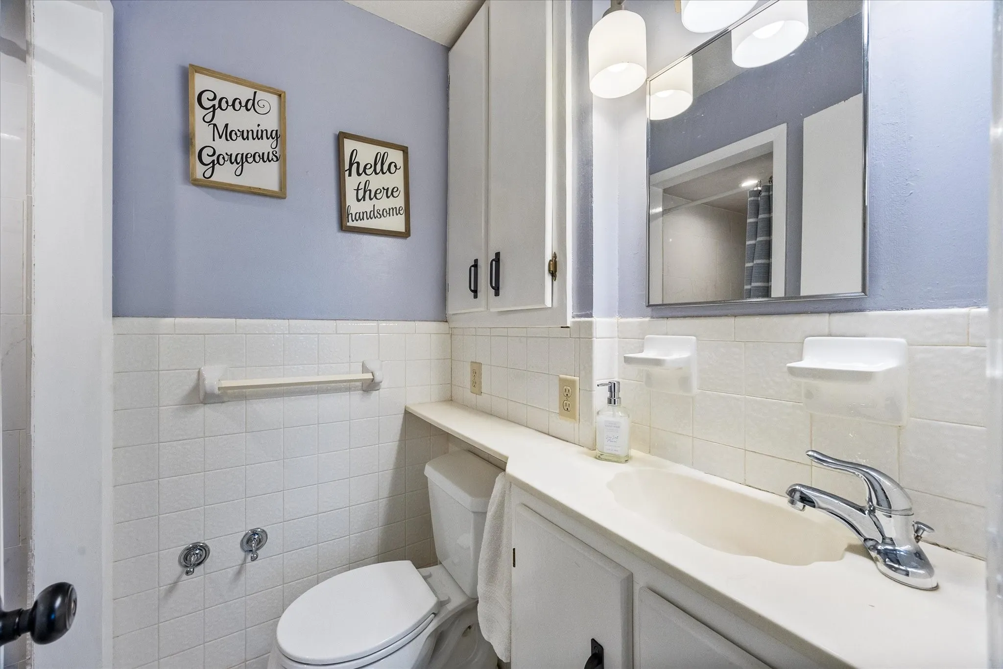 Bathroom with vanity, tile walls, wainscoting, and a shower