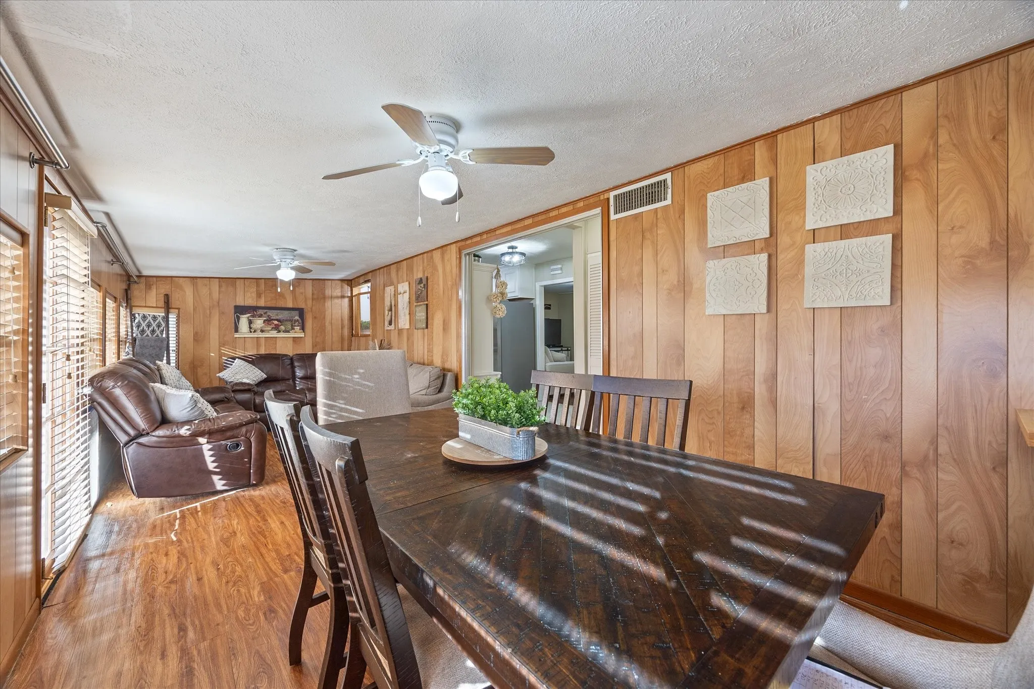 Dining area with a textured ceiling, wood finished floors, and wood walls