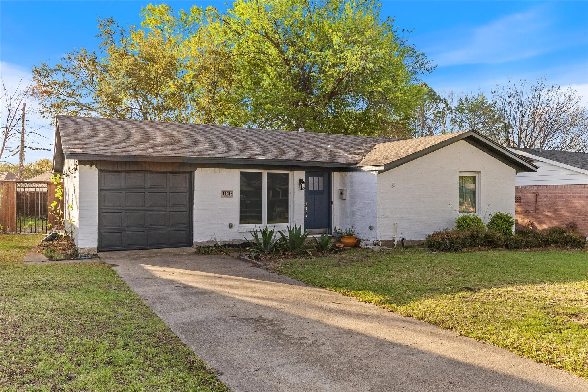 View of front facade with concrete driveway, a garage, brick siding, and roof with shingles
