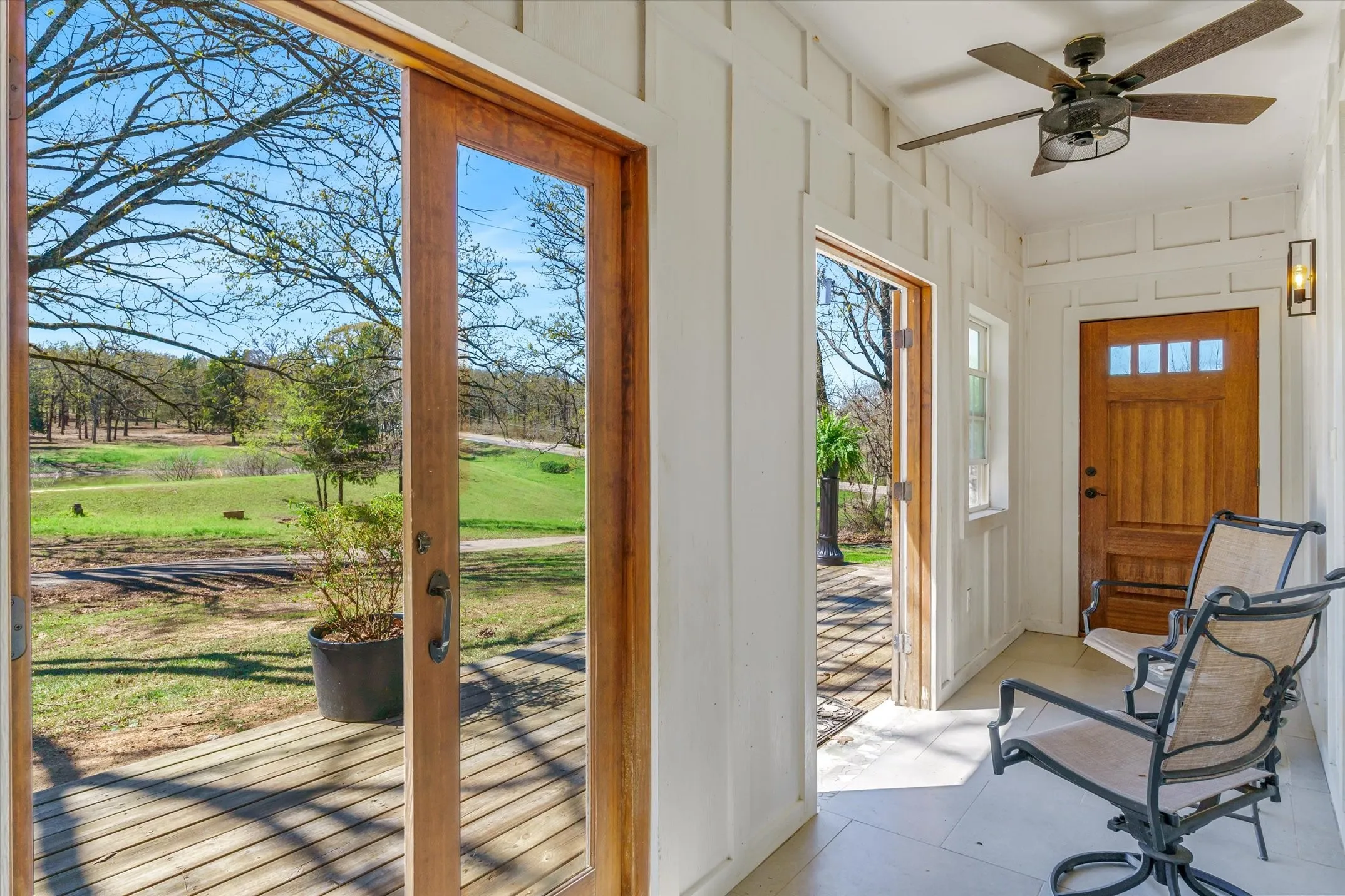 Enclosed porch with a ceiling fan and beautiful view overlooking pond.