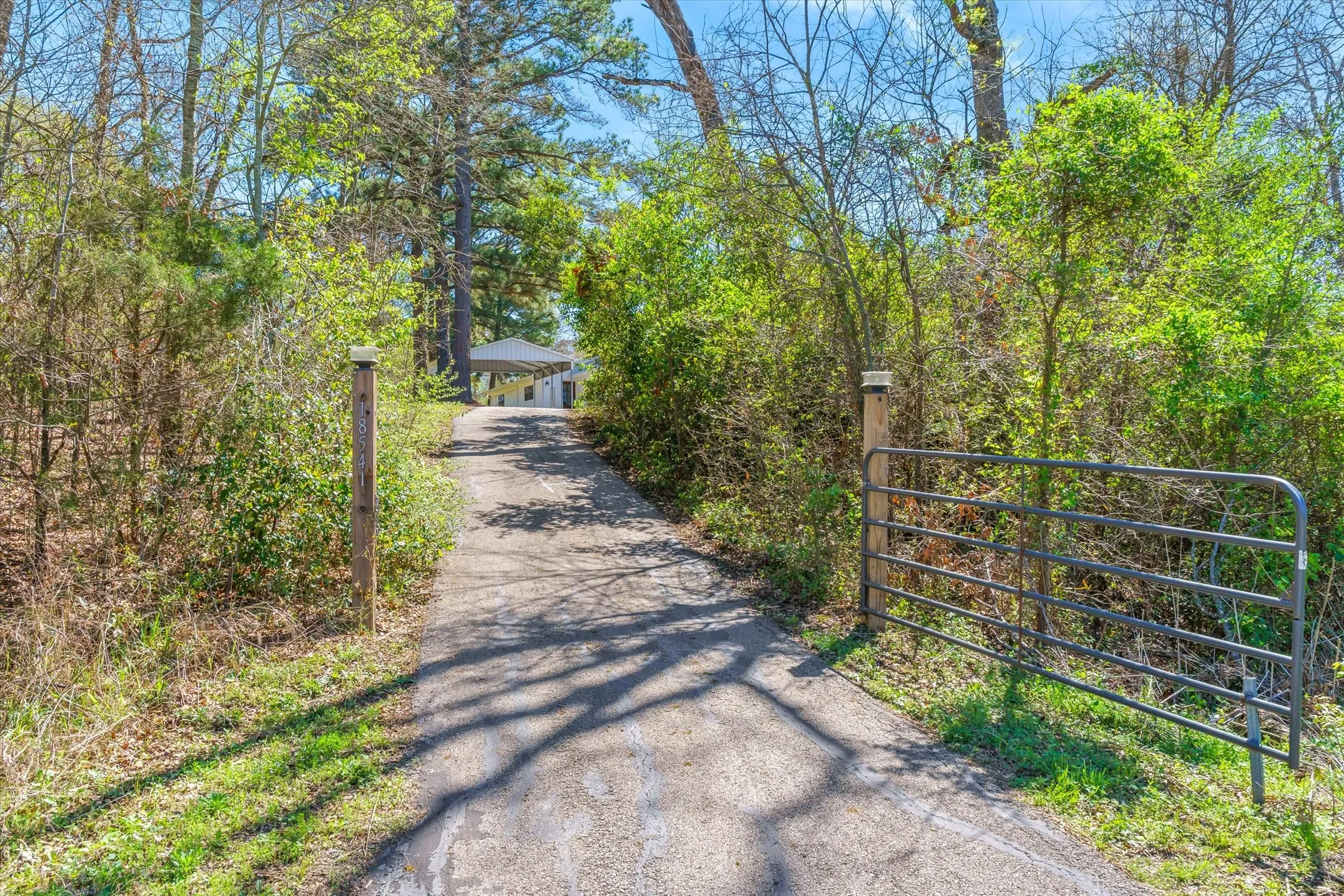 View of asphalt driveway with a gated entry