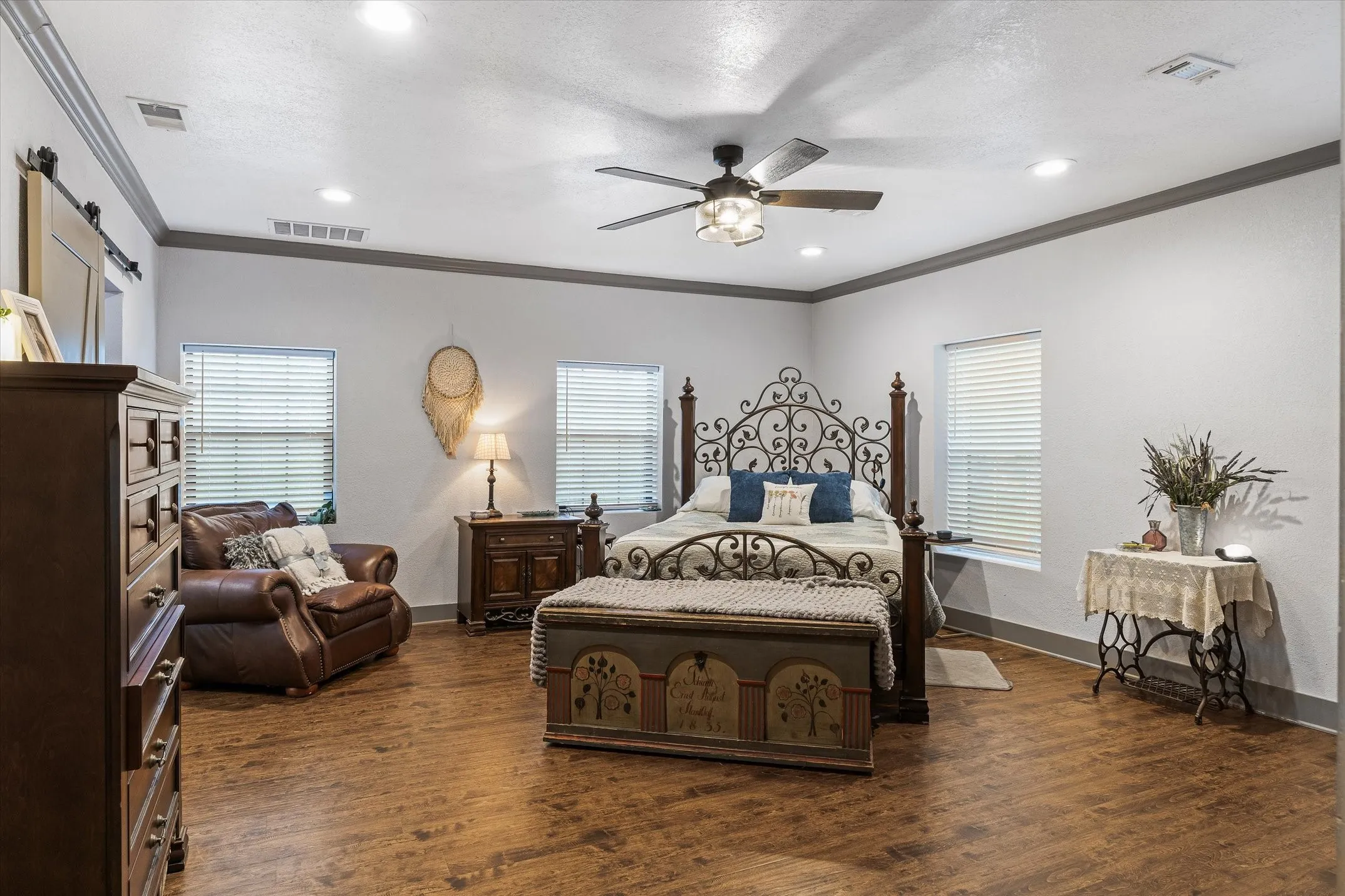 Step down into the primary bedroom featuring crown molding, a ceiling fan, dark wood-style floors, and recessed lighting