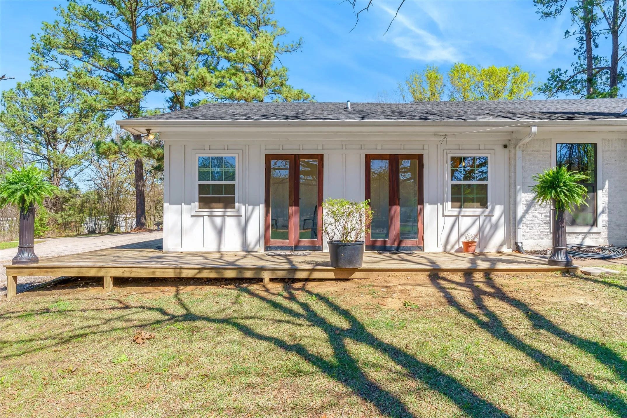 Back of house featuring a shingled roof, a lawn, and board and batten siding. Open the doors to enjoy the breeze and view of pond.