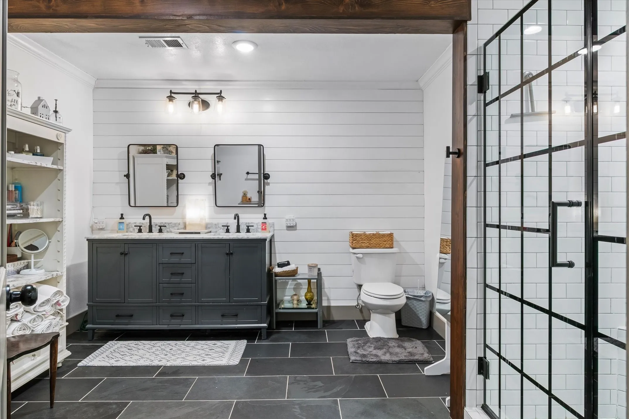 Full bathroom with crown molding, double vanity, wooden walls, and a stall shower