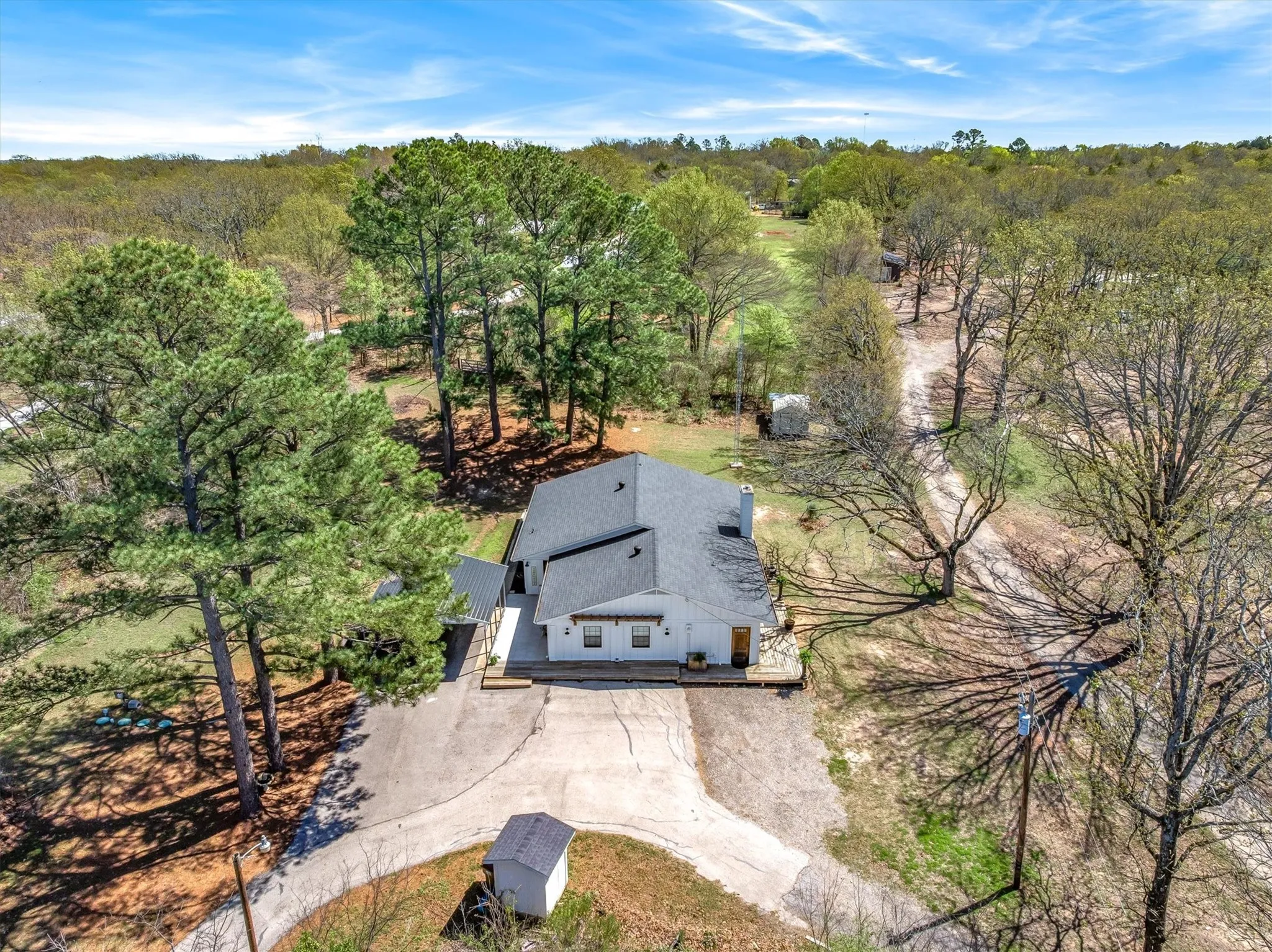 View of subject property with scattered trees and set back off the road