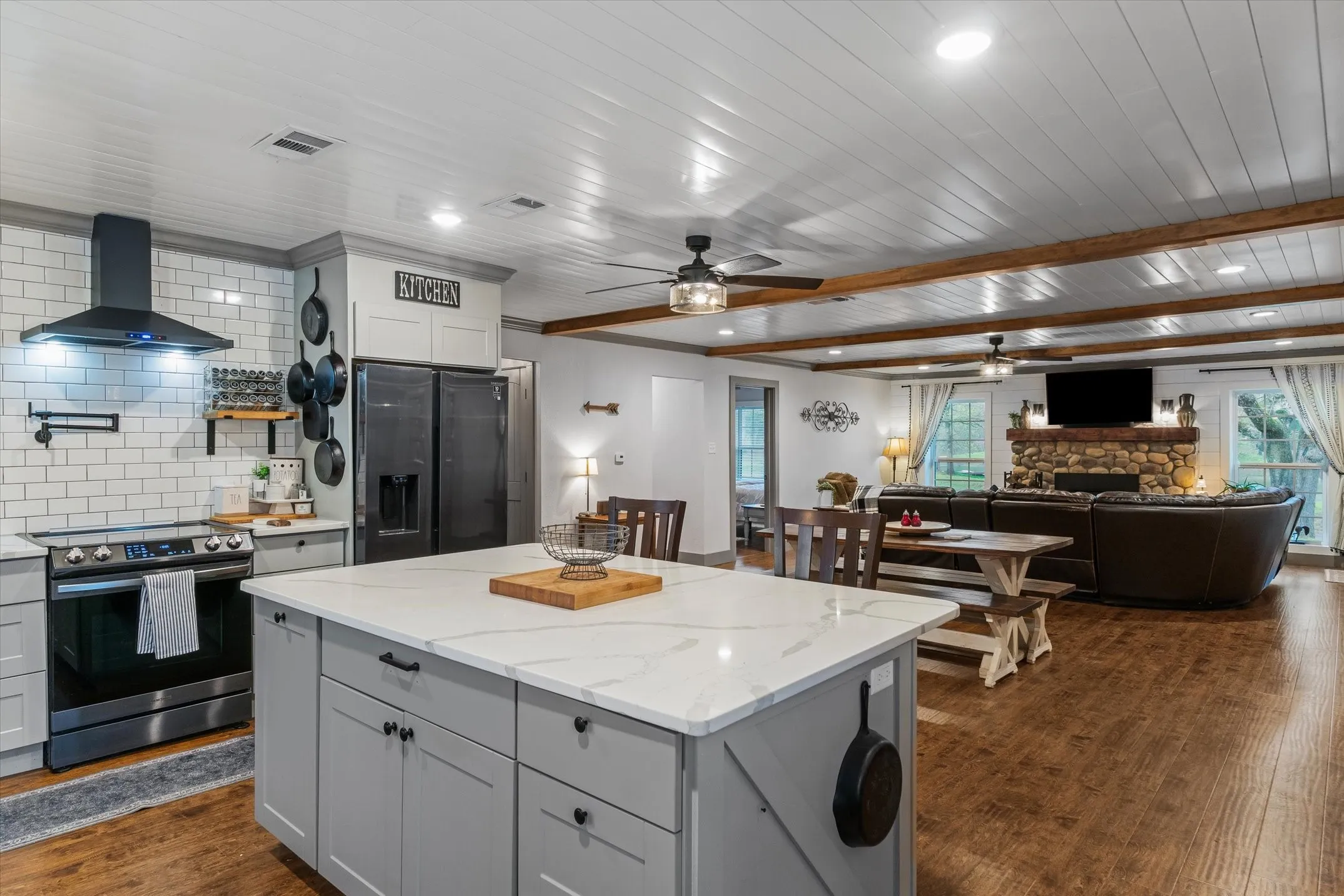 Kitchen featuring a ceiling fan, stainless steel electric stove, open floor plan, a kitchen island, and black refrigerator with ice dispenser