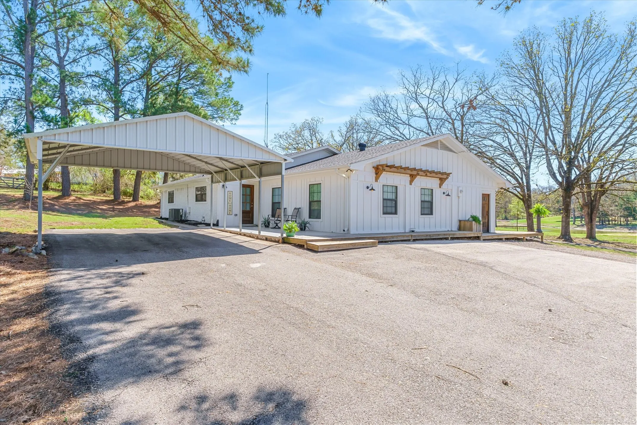 View of front of property featuring asphalt driveway, board and batten siding, a carport, and a wooden deck